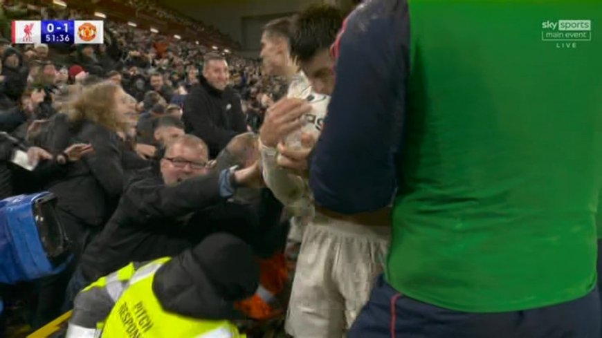 Man United fans helped up by stewards after advertising board collapses during goal celebrations at Liverpool