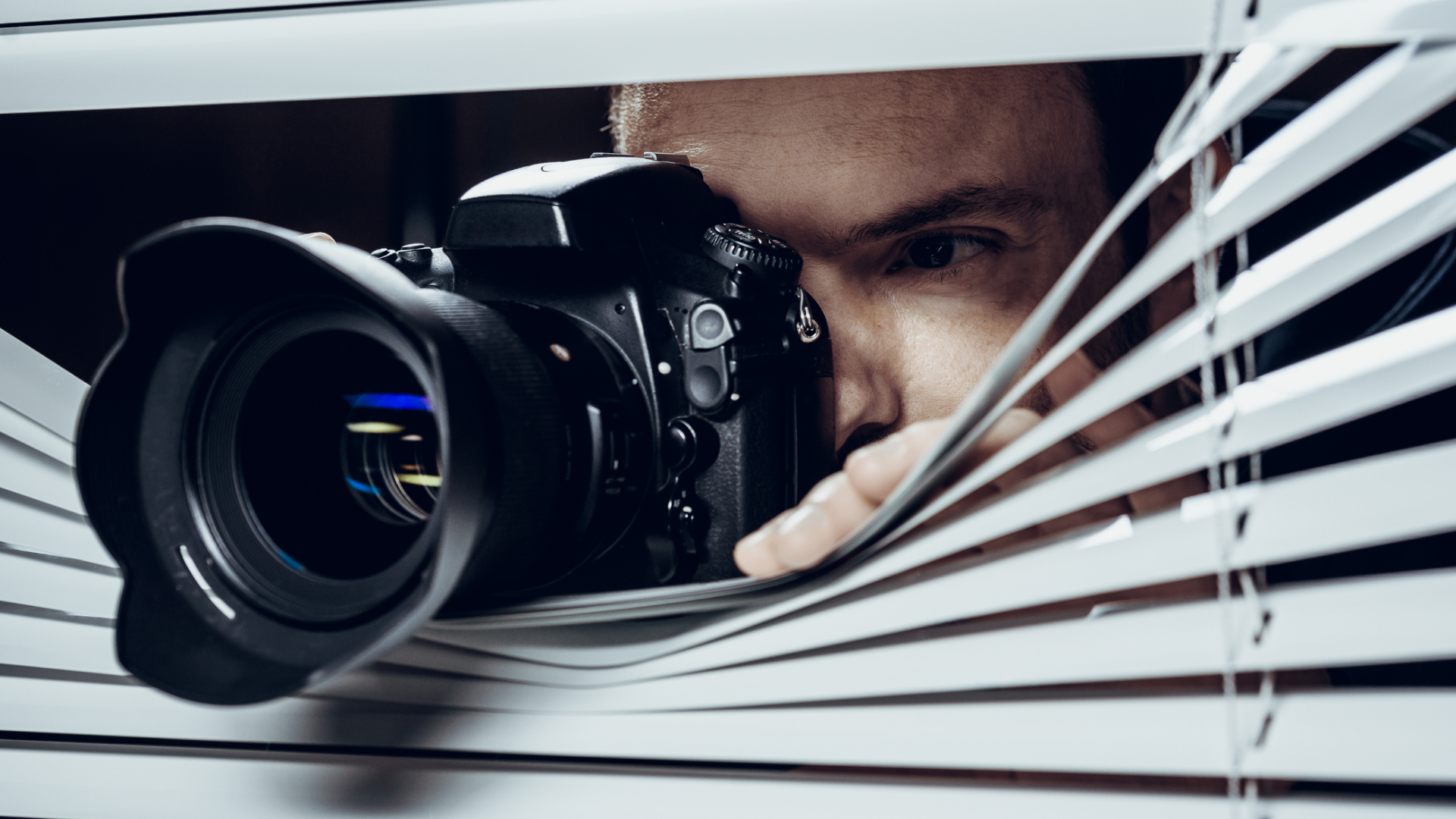A creepy dude snapping pics through blinds.