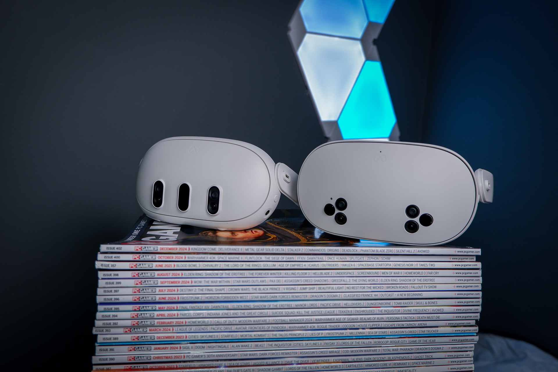 A Meta Quest 3S, alongside a Quest 3 and Quest 2, on a stack of PC Gamer magazine.