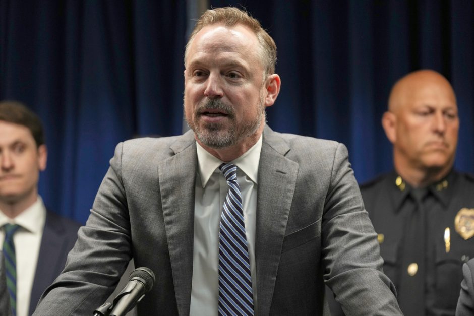 bearded man in suit and tie speaks into microphone