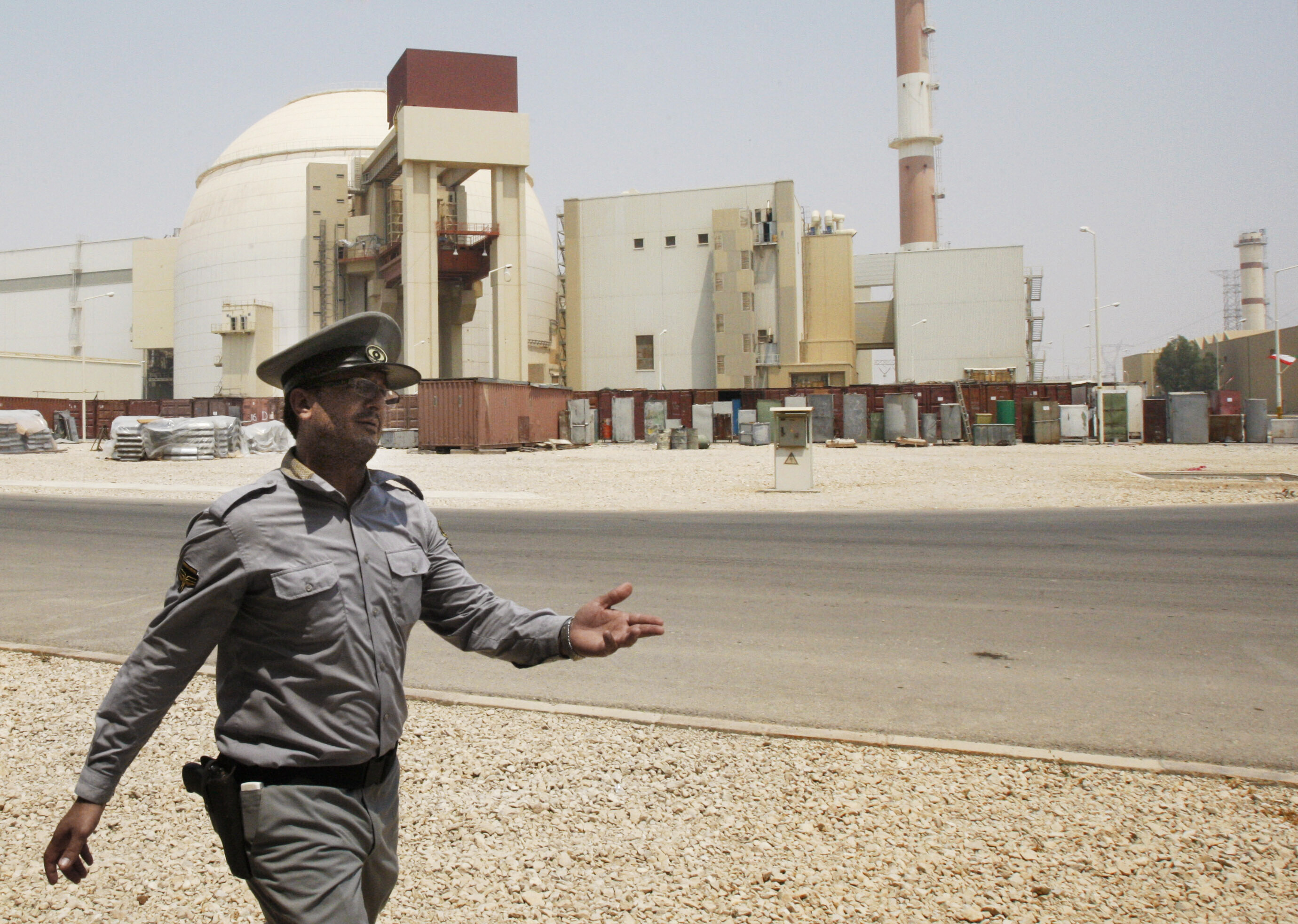 FILE - In this Aug. 21, 2010 file photo, an Iranian security officer directs media at the Bushehr nuclear power plant, with the reactor building seen in the background, just outside the southern city of Bushehr, Iran. (AP Photo/Vahid Salemi, File)