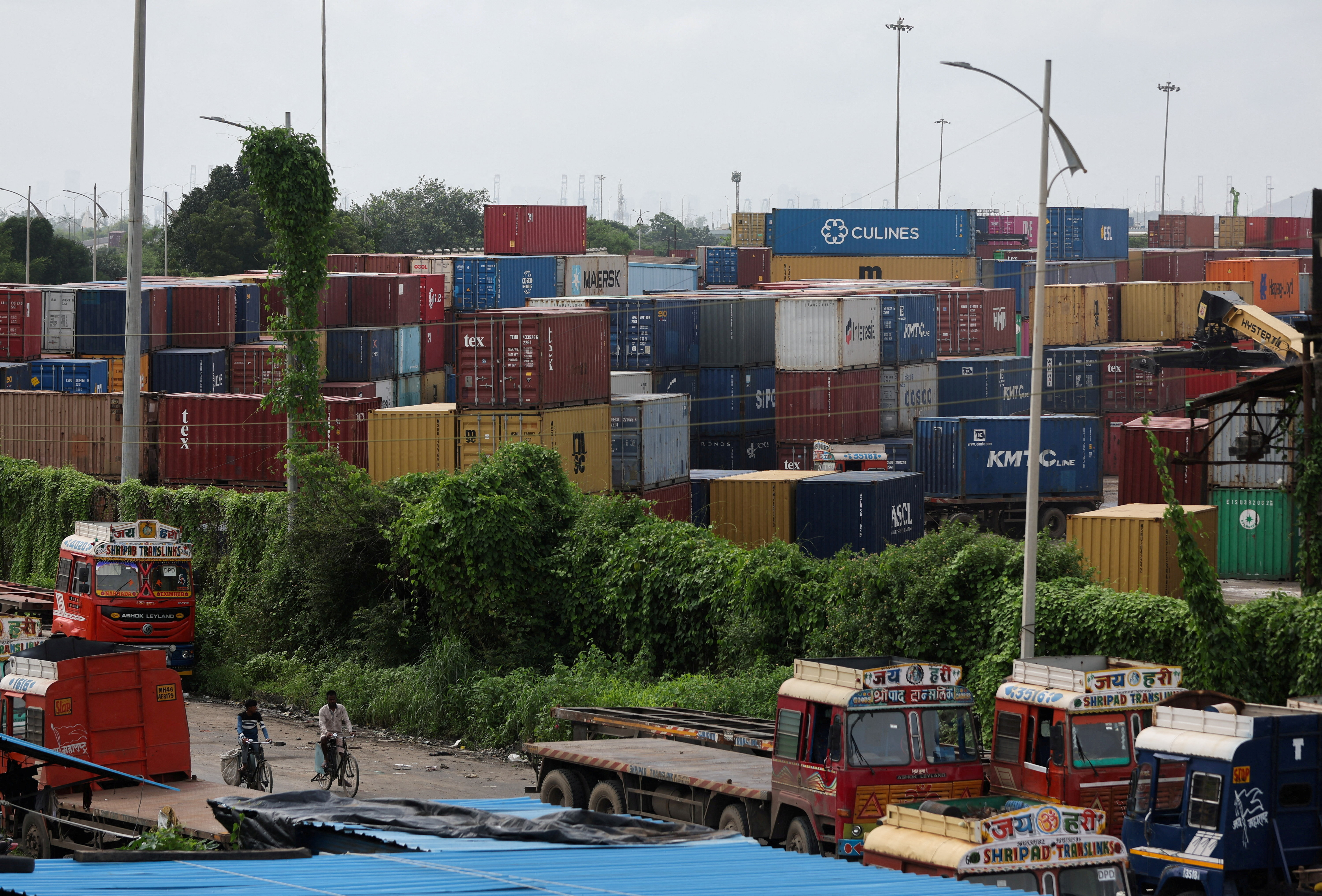 FILE PHOTO: Men ride bicycles past shipping containers at a warehouse in Navi Mumbai, India, August 11, 2025. REUTERS/Francis Mascarenhas/File Photo