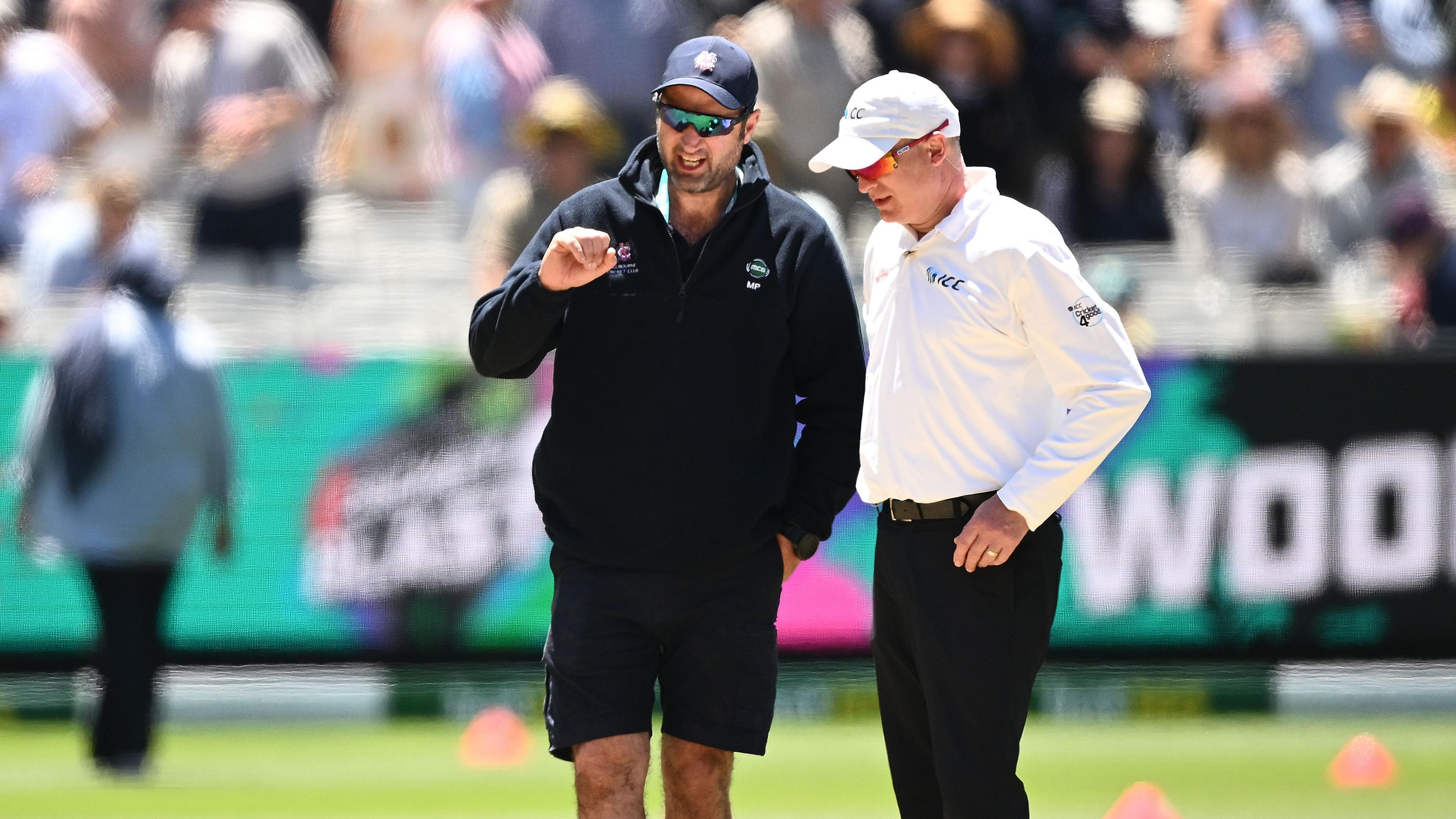 Melbourne Cricket Ground head groundsman Matt Page (left) inspects the pitch during the lunch break on day two