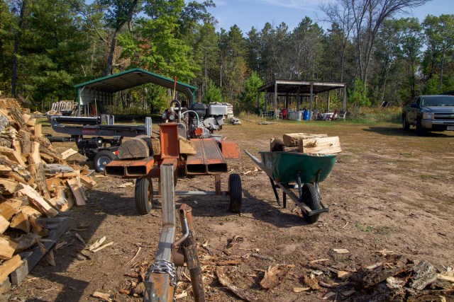 woodpile, wheel barrow and log-splitting tool outdoors