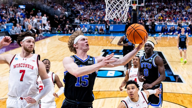BYU Cougars forward Richie Saunders (15) lays the ball up past Wisconsin Badgers forward Carter Gilmore (7) during a second-round college basketball game in the NCAA Tournament held at Ball Arena in Denver on Saturday, March 22, 2025.