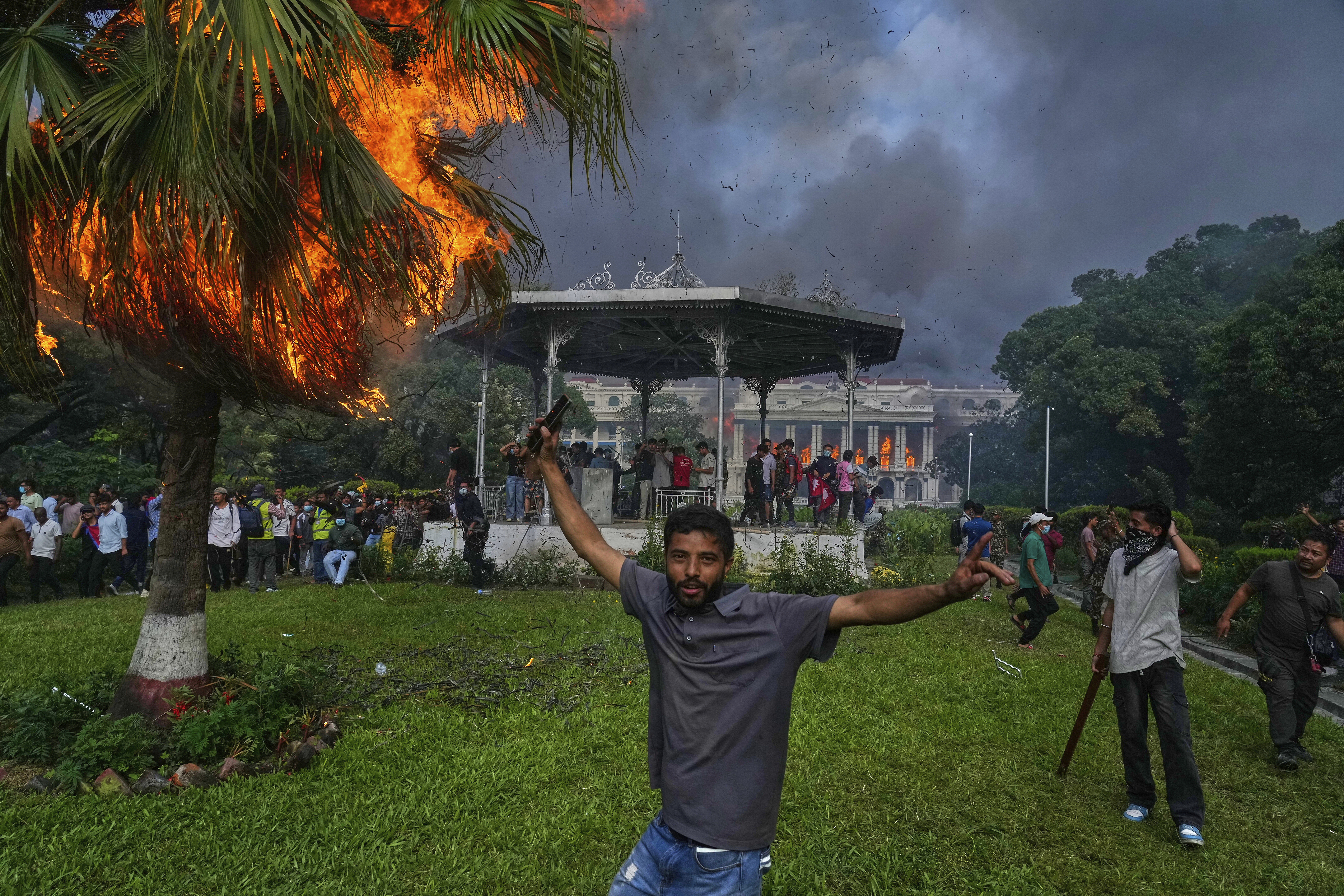 Protesters celebrate at the Singha Durbar, the seat of Nepal's government's various ministries and offices, after it was set on fire during a protest against a social media ban and corruption in Kathmandu, Nepal, Tuesday, Sept. 9, 2025. (AP Photo/Niranjan Shrestha)