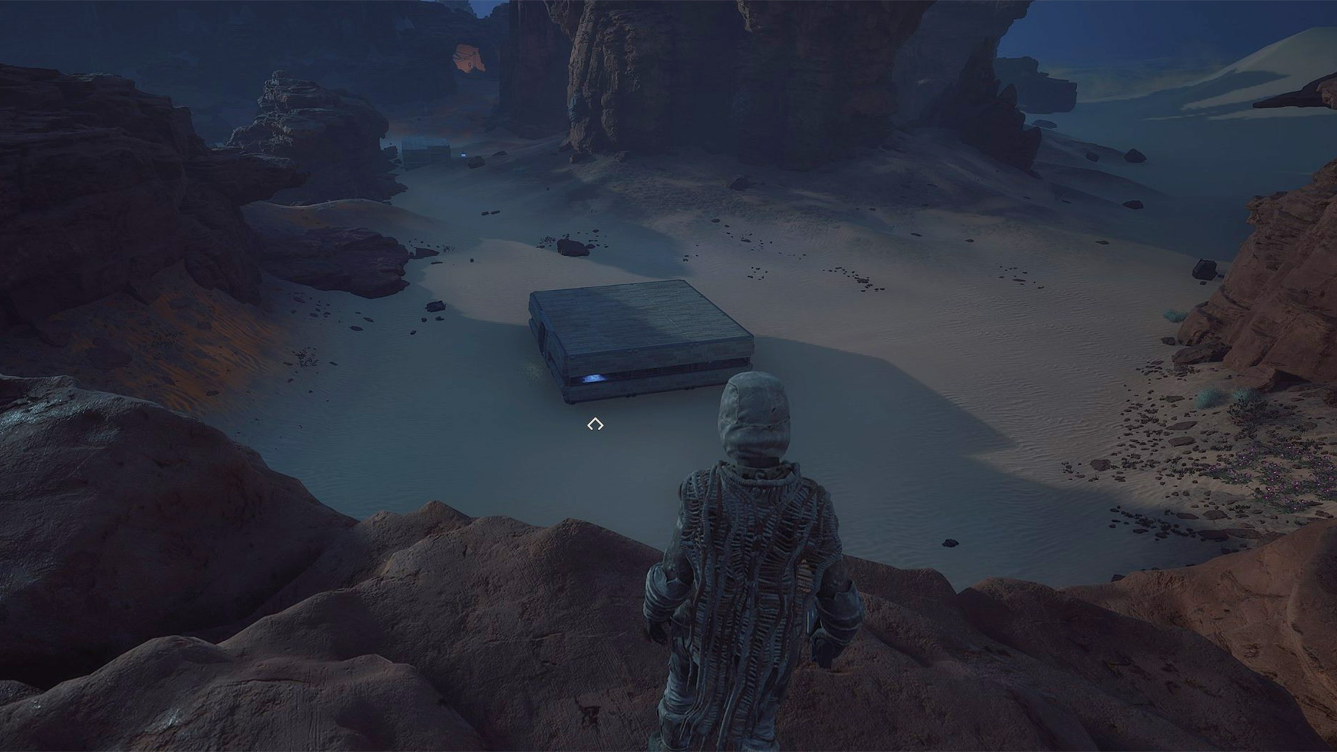 Looking down from a nearby mountain on a player-made house in Dune: Awakening. The house is flat and square-shaped. A bit slanted, so it looks like a big PS4.