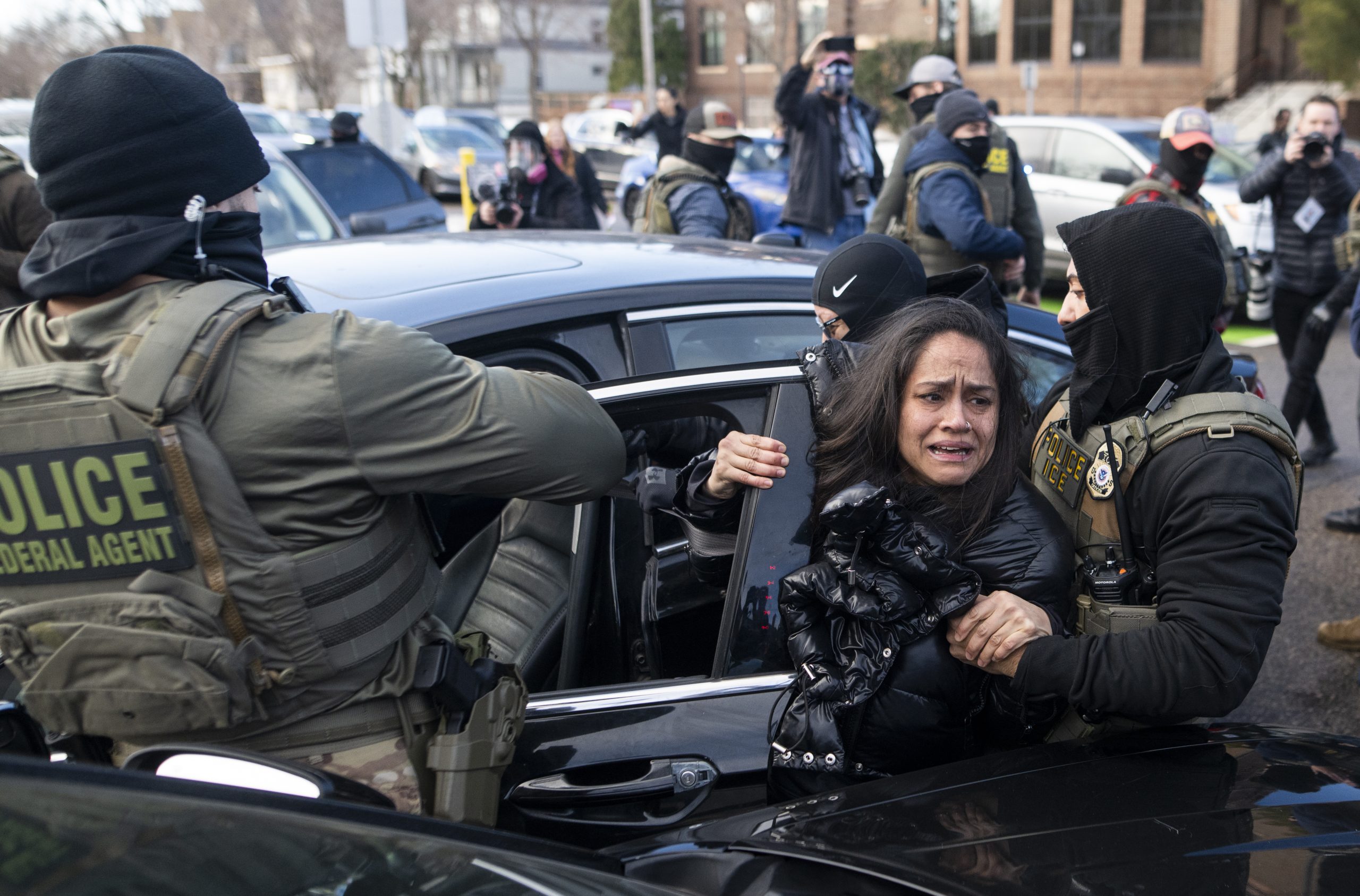 ICE agents detain a woman after pulling her from a car on January 13, 2026 in Minneapolis, Minnesota. Photo by Stephen Maturen/Getty Images