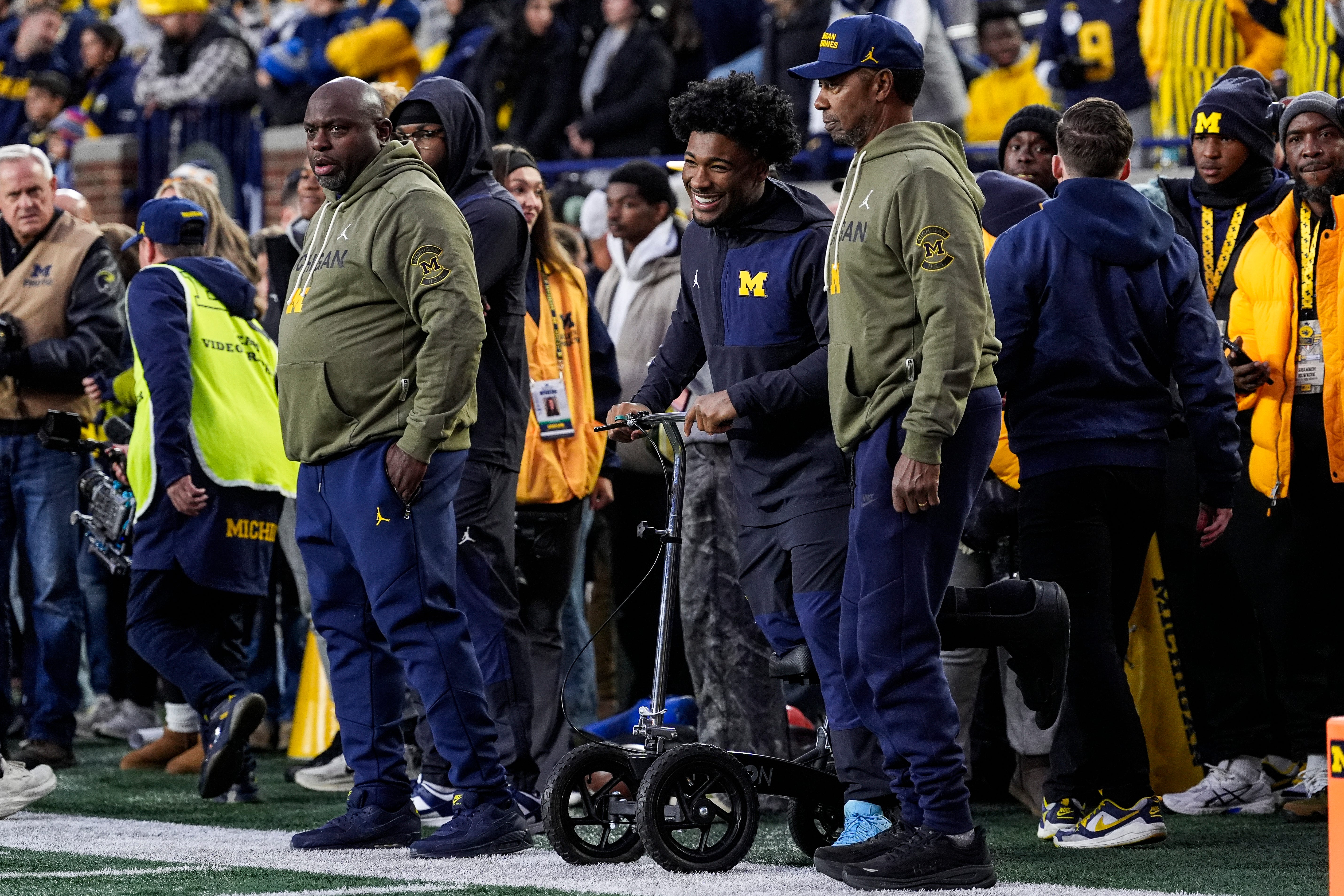 Injured Michigan running back Justice Haynes, center, talks to running backs coach Tony Alford, left, and Fred Jackson, senior offensive analyst/running backs, during warmups ahead of the Purdue game at Michigan Stadium in Ann Arbor on Saturday, November 1, 2025.