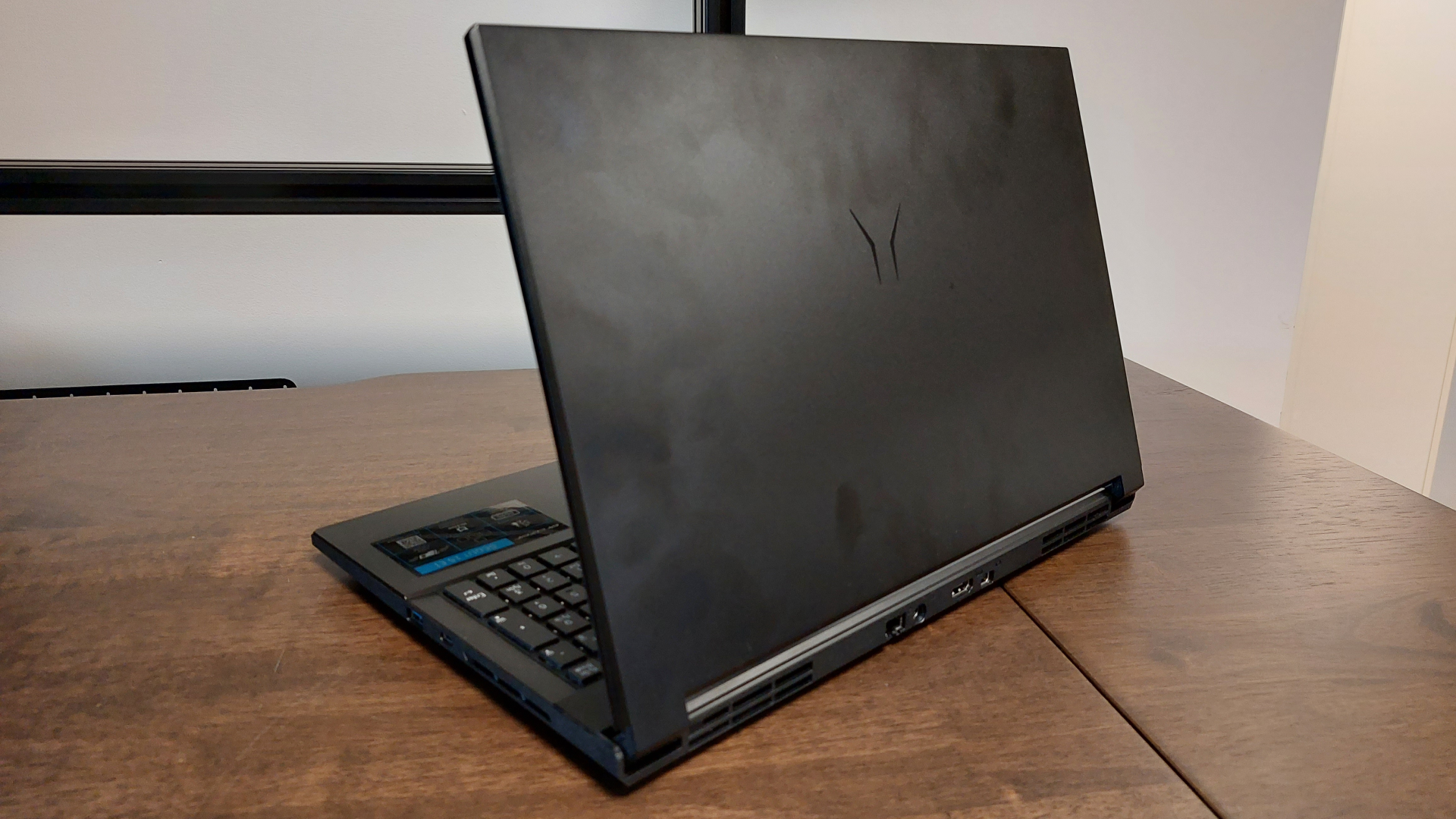 The Erazer Scout 15 E1 RTX 5050 gaming laptop is seen on a wooden desk in a brightly lit, neutral toned office.