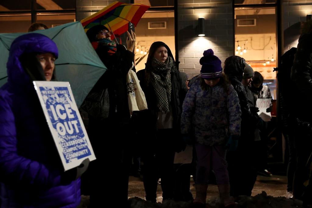 protesters gather and one holds a sign that says 'ice out'
