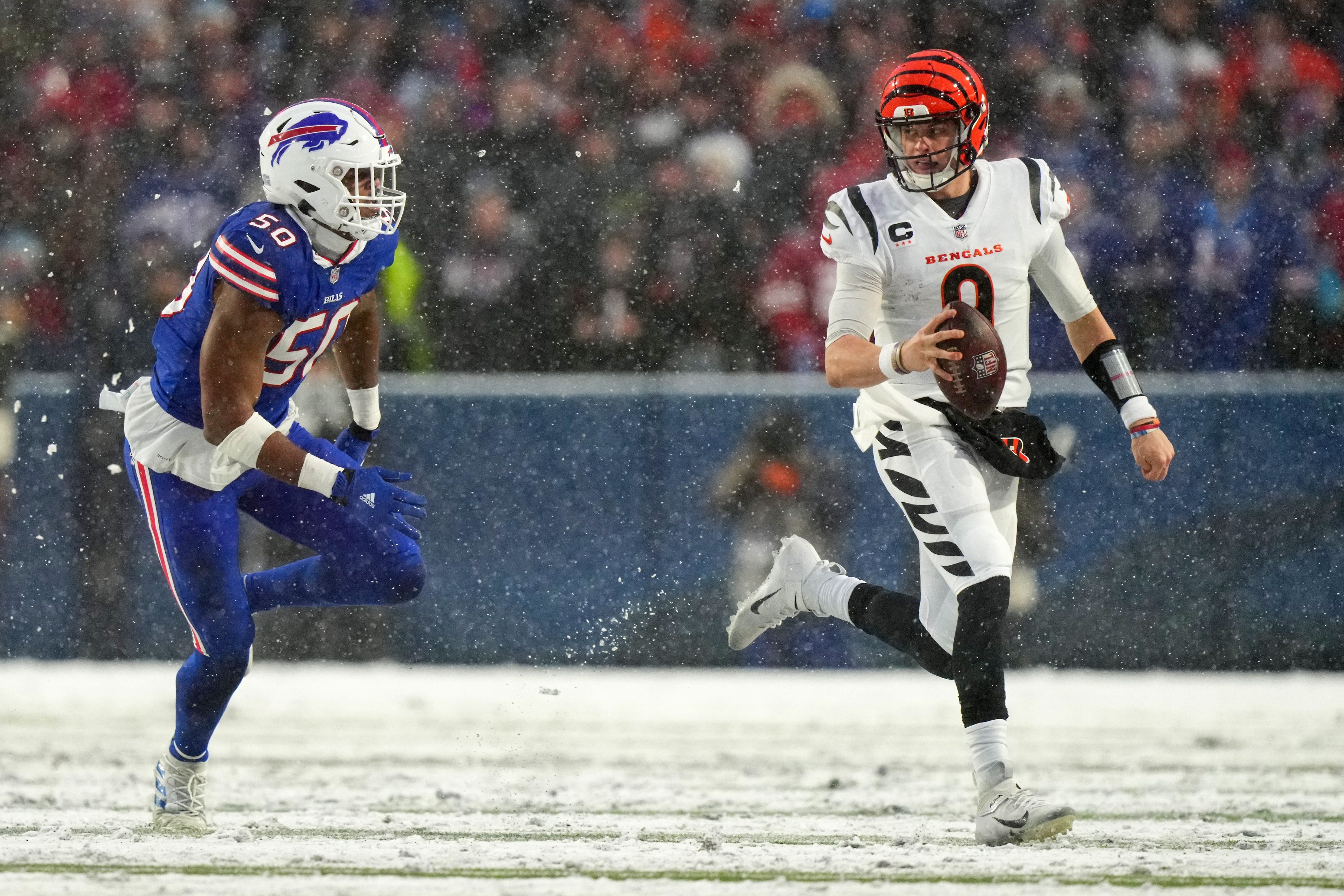 Cincinnati Bengals quarterback Joe Burrow (9) carries the ball as Buffalo Bills defensive end Greg Rousseau (50) defends in the second quarter during an NFL divisional playoff football game between the Cincinnati Bengals and the Buffalo Bills, Sunday, Jan. 22, 2023, at Highmark Stadium in Orchard Park, N.Y. Cincinnati Bengals At Buffalo Bills Afc Divisional Jan 22 1207