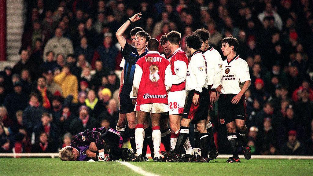 Peter Schmeichel lies injured after being fouled by Ian Wright