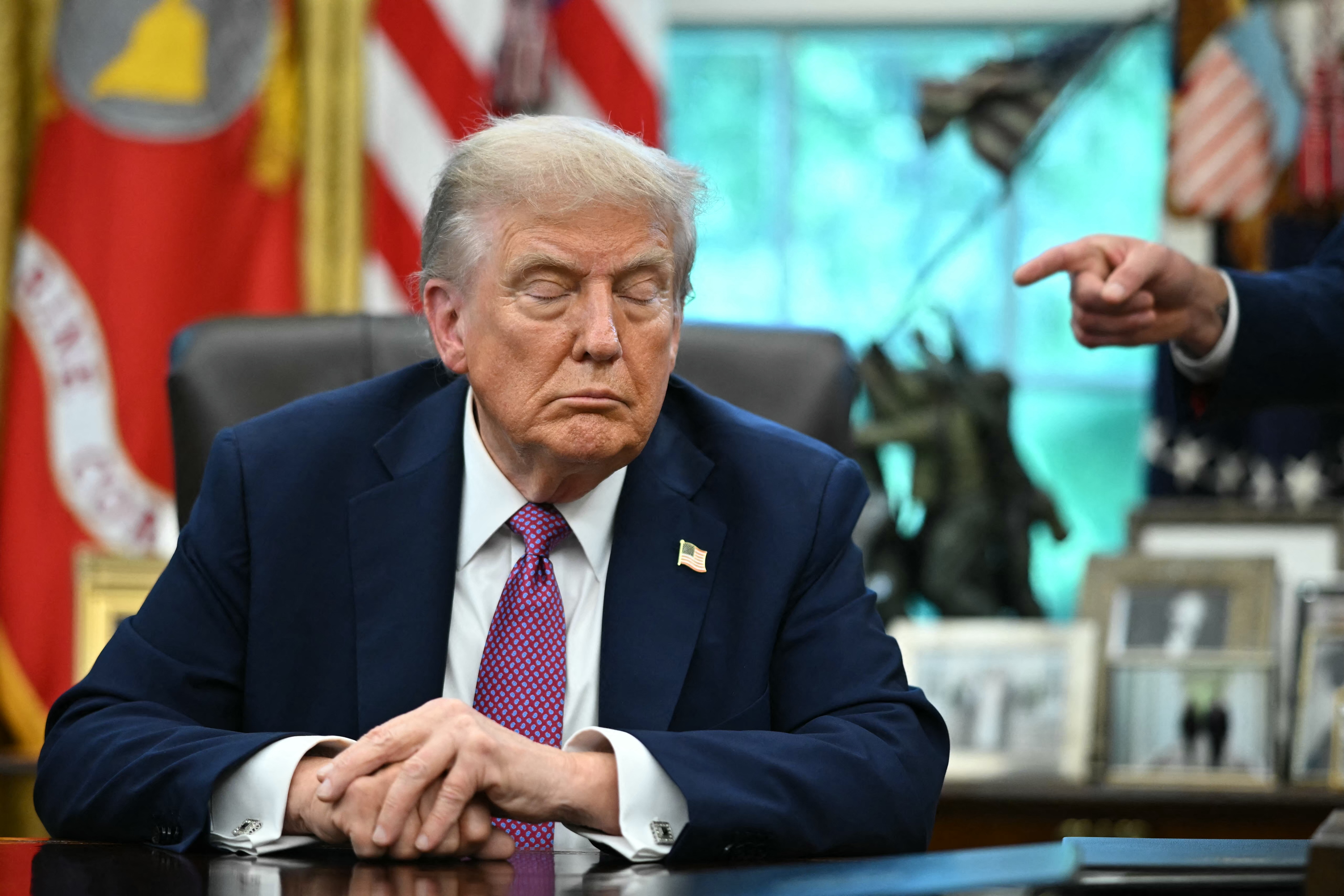 US President Donald Trump reacts as the Secretary of Defense Pete Hegseth points at him after signing executive orders in the Oval Office of the White House in Washington, DC on September 5, 2025.