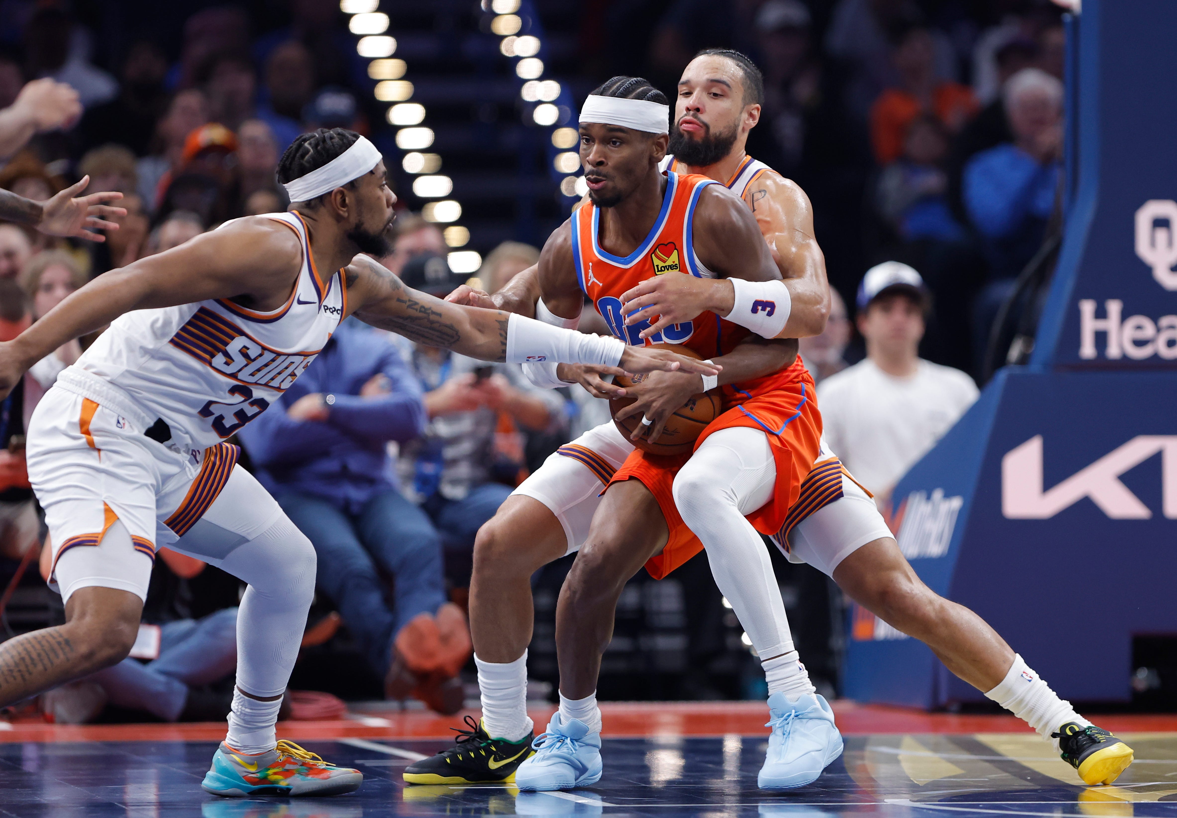Nov 28, 2025; Oklahoma City, Oklahoma, USA; Oklahoma City Thunder guard Shai Gilgeous-Alexander (2) is defended by Phoenix Suns guard Jordan Goodwin (23) and forward Dillon Brooks (3) during the second quarter at Paycom Center. Mandatory Credit: Alonzo Adams-Imagn Images