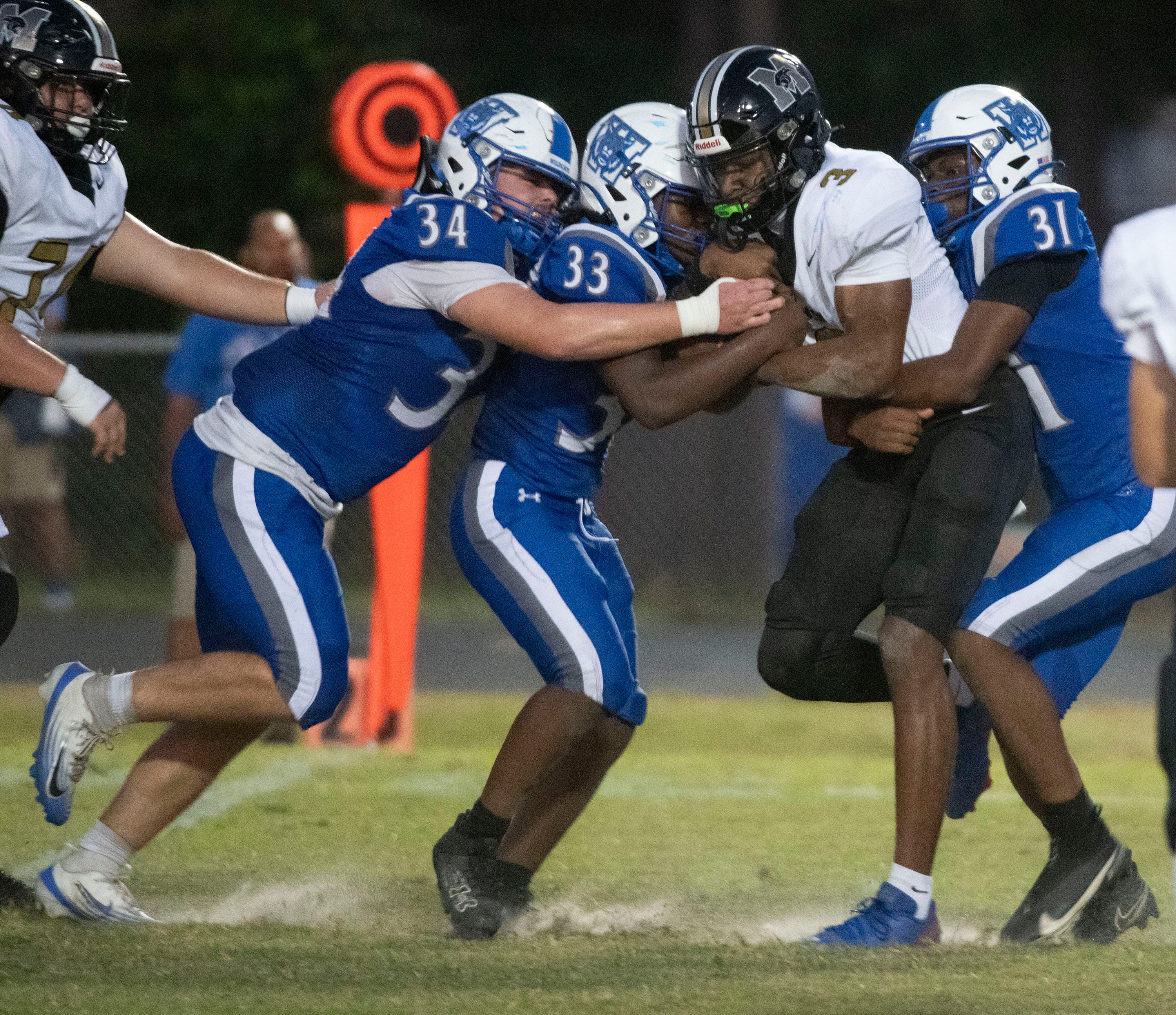 Milton quarterback Kaiden Hall (No. 3) gets gang tackled by Washington's Kolby Saladino (No. 34), Leroy Murphy (No. 33), and Walt Baker (No. 31) for a loss of yards during the first half of Thursday's non-district game on Sept. 4, 2025.