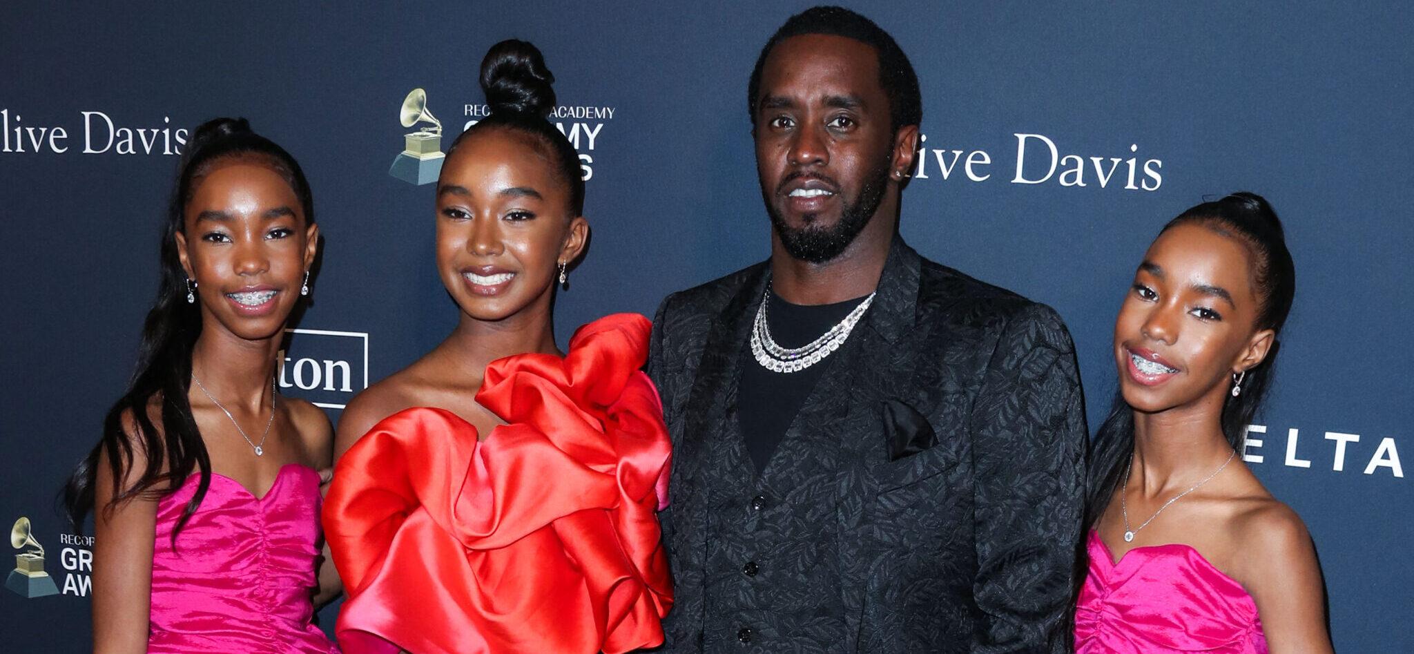 Diddy posing with his daughters on the red carpet.
