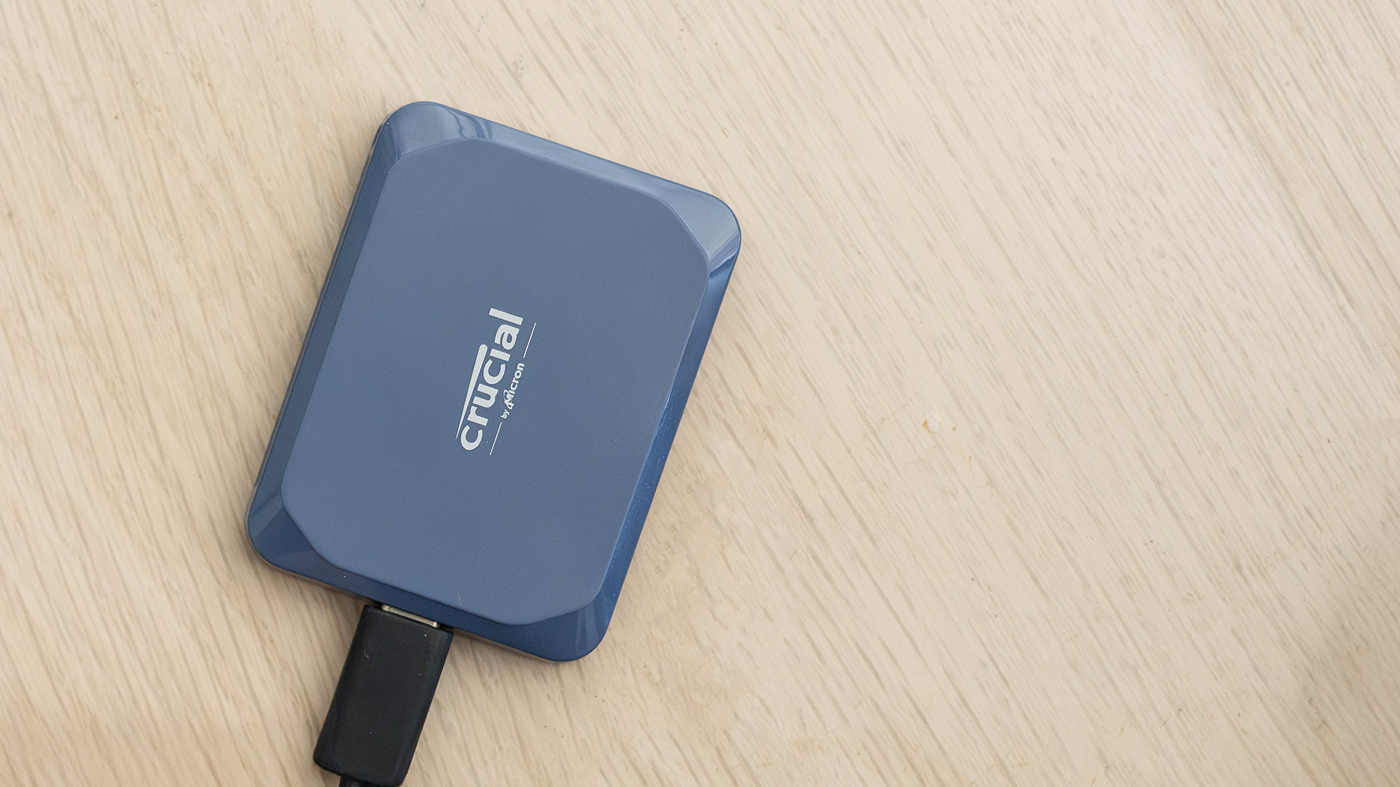 A Crucial X10 external SSD in blue with USB Type-C connector cable.