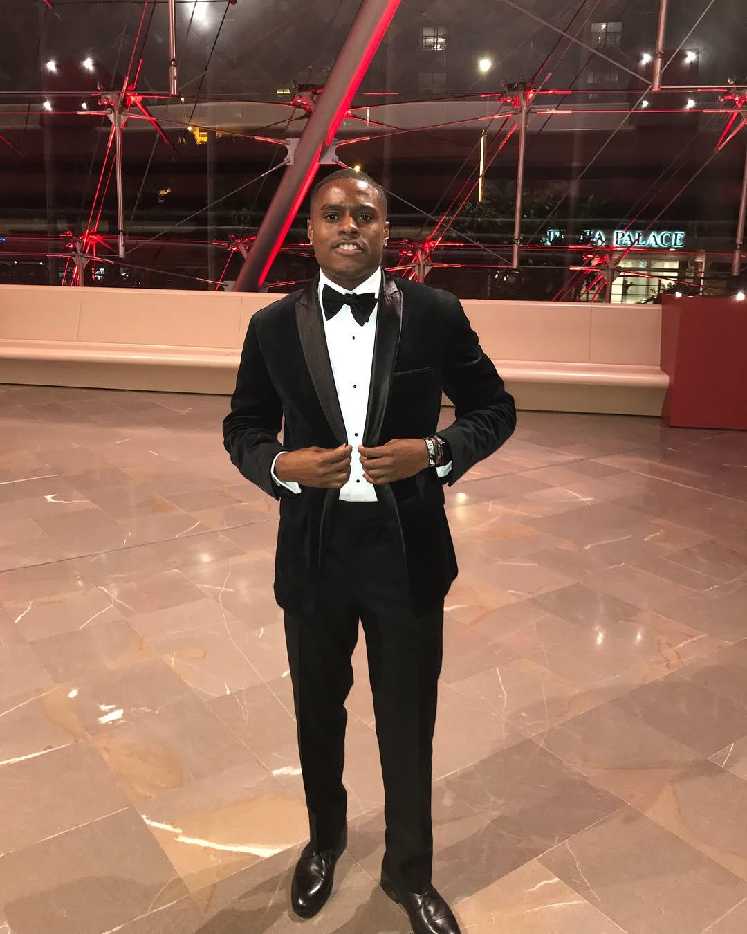 Olympian Christian Coleman posing in a black suit.