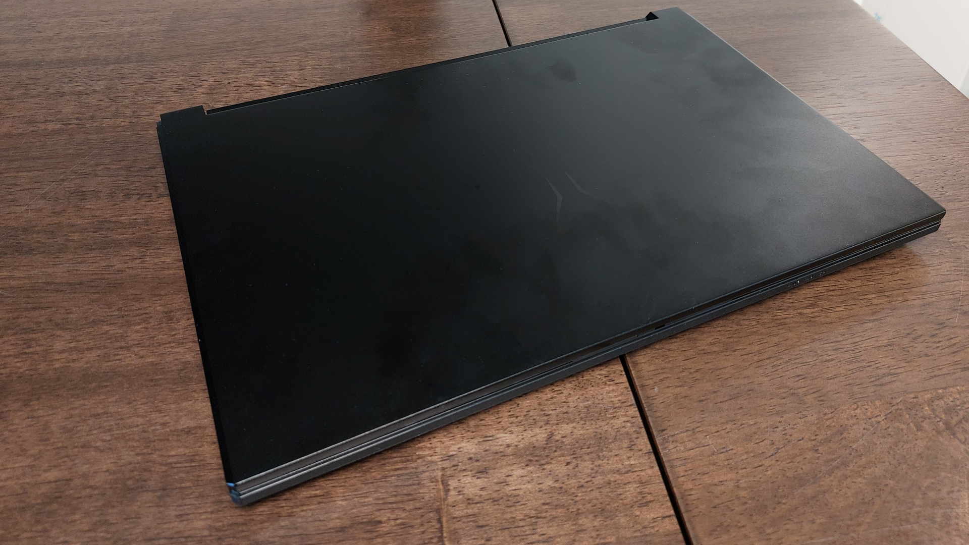 The Erazer Scout 15 E1 RTX 5050 gaming laptop is seen on a wooden desk in a brightly lit, neutral toned office.