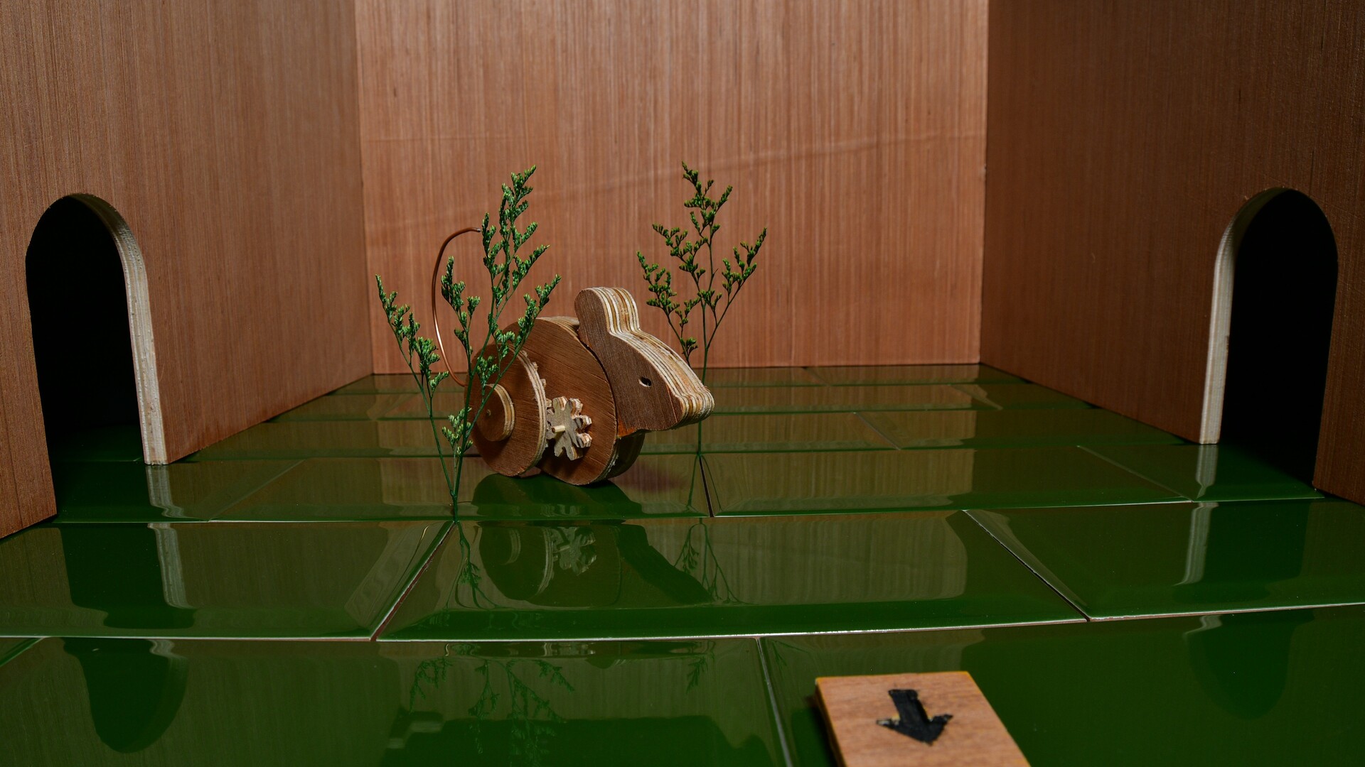 Wooden mechanical mouse in empty room with green tile in Ealu.