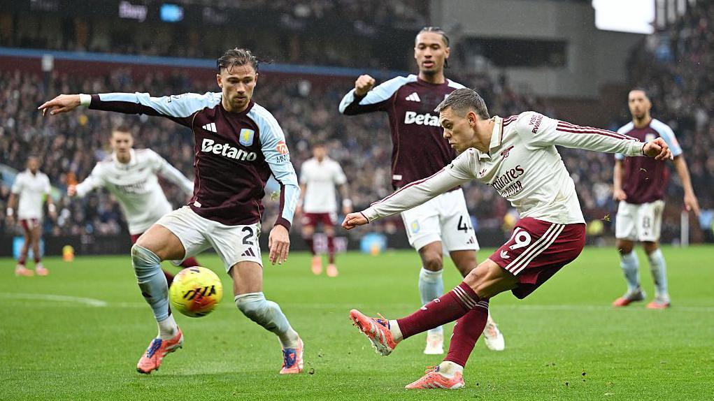 Leandro Trossard shoots under pressure from Matty Cash