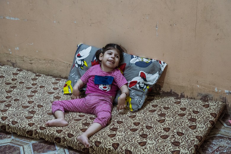 Ten-year-old Jannat lies on a mattress, paralyzed since birth and dependent on her family’s care. Photo by Jaclynn Ashly.