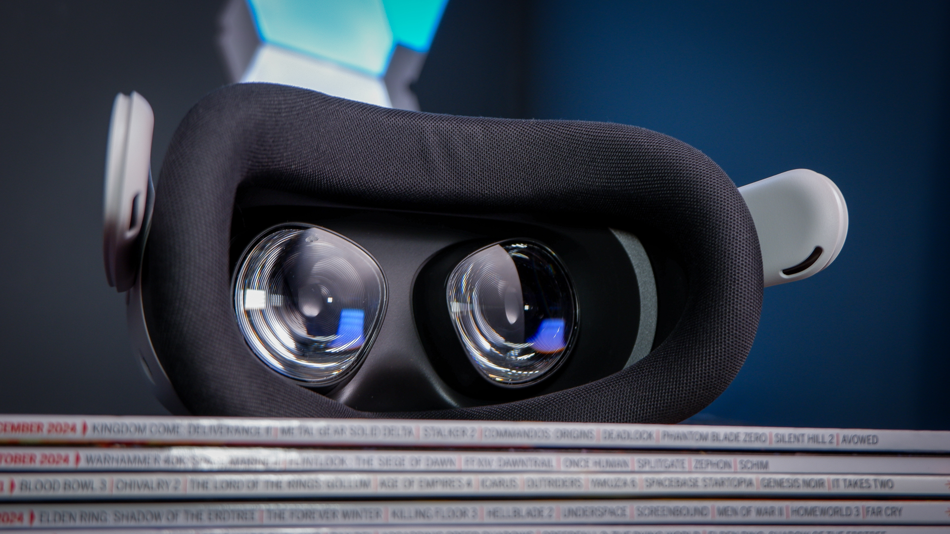 A Meta Quest 3S, alongside a Quest 3 and Quest 2, on a stack of PC Gamer magazine.