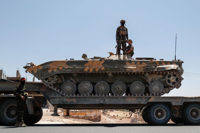Syrian government forces stand on an armored personnel carrier carried on a truck, as they withdraw from Sweida city, southern Syria, Tuesday, July 15, 2025.(AP Photo/Ghaith Alsayed)