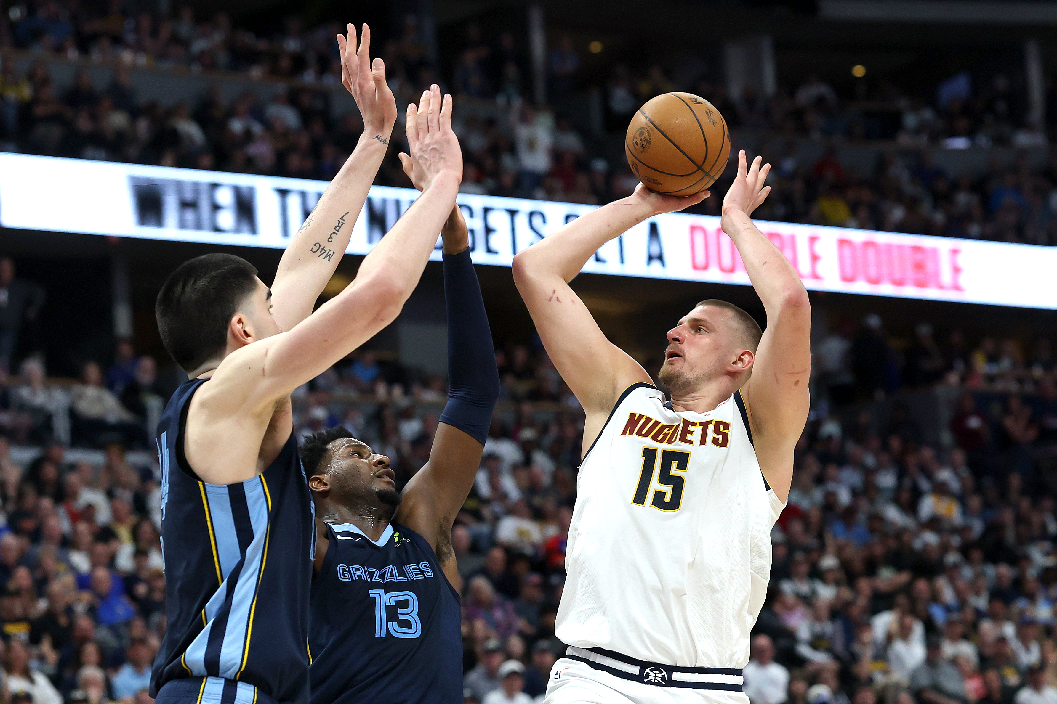 DENVER, COLORADO - APRIL 11: Nikola Jokic #15 of the Denver Nuggets puts up a shot against Zach Edey #14 and Jaren Jackson Jr. #13 of the Memphis Grizzlies in the fourth quarter at Ball Arena on April 11, 2025 in Denver, Colorado. NOTE TO USER: User expressly acknowledges and agrees that, by downloading and or using this photograph, User is consenting to the terms and conditions of the Getty Images License Agreement. (Photo by Matthew Stockman/Getty Images)