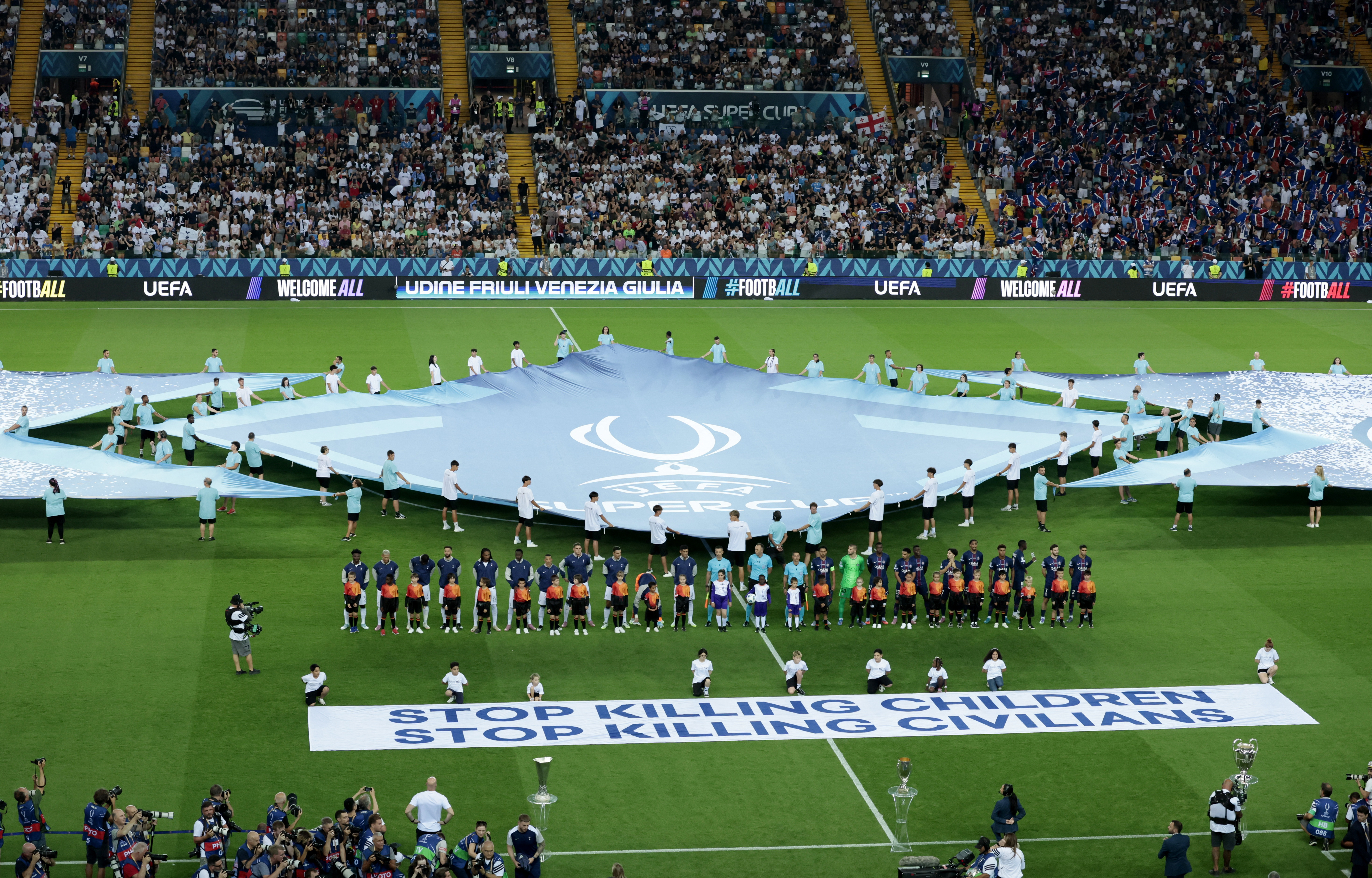 Soccer Football - UEFA Super Cup - Final - Paris St Germain v Tottenham Hotspur - Bluenergy Stadium, Udine, Italy - August 13, 2025 Nine children who are refugees in Italy from different conflict zones, Afghanistan, Iraq, Nigeria, Palestine and Ukraine, display a banner saying "STOP KILLING CHILDREN