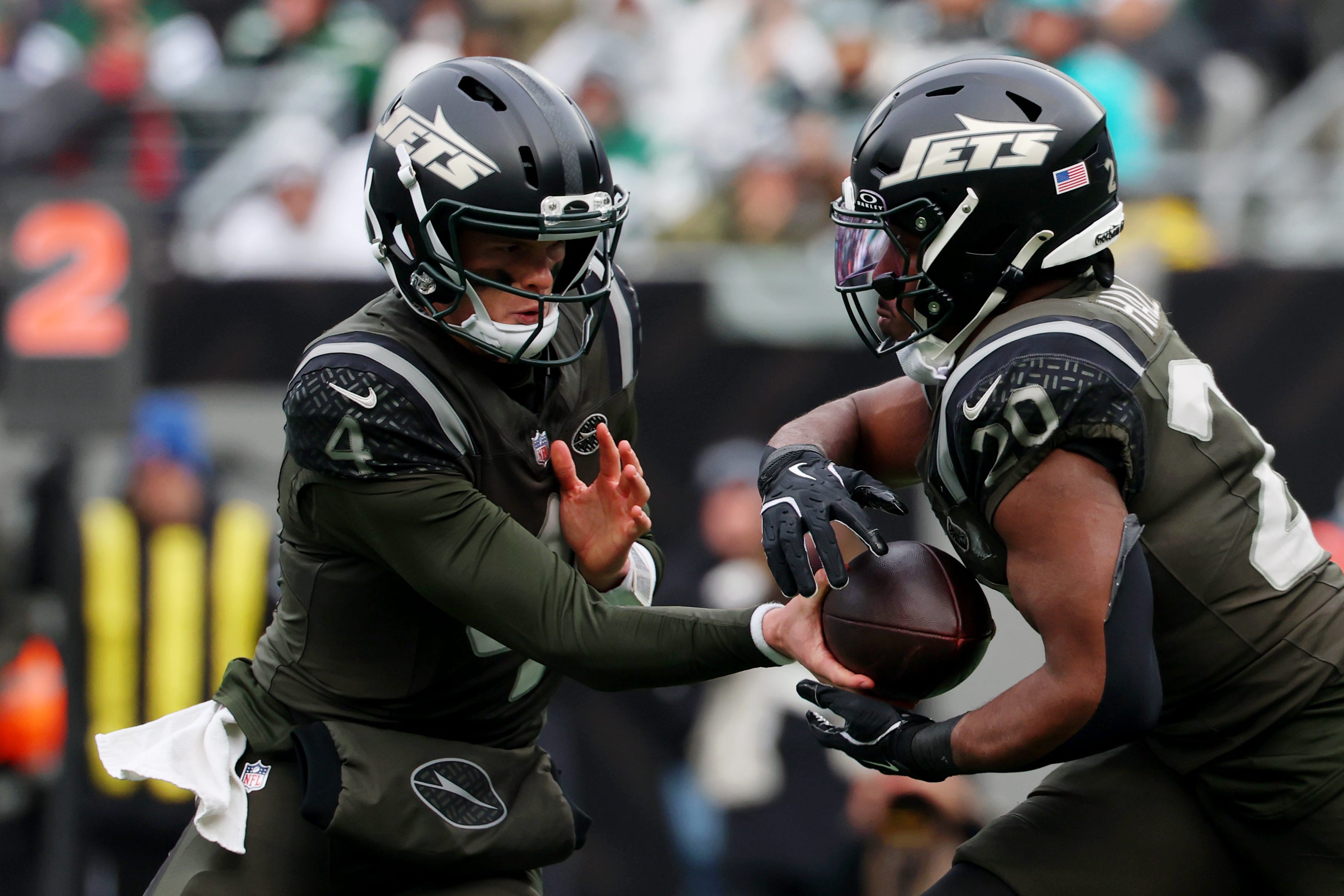 Dec 7, 2025; East Rutherford, New Jersey, USA; New York Jets quarterback Brady Cook (4) hands the ball off to running back Breece Hall (20) during the first half at MetLife Stadium. Mandatory Credit: Ed Mulholland-Imagn Images
