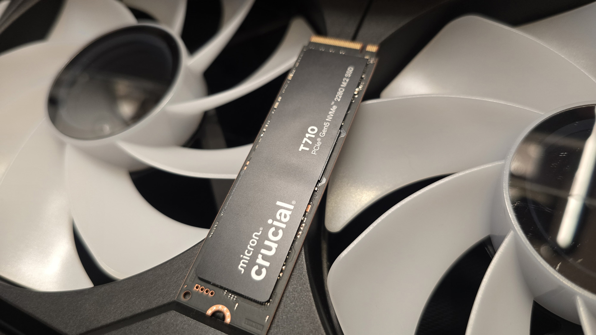 A Crucial T710 SSD on some fans ready to be installed inside a gaming PC.