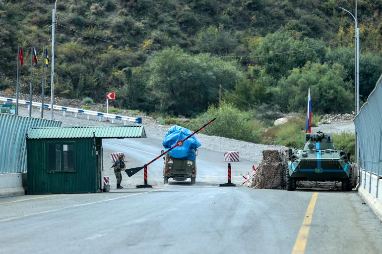 Sergey Astsetryan, an ethnic Armenian resident of Nagorno-Karabakh, drives his Soviet-made vehicle past Russian peacekeepers after been checked by Azerbaijani border guard servicemen at the Lachin checkpoint on the way from Nagorno-Karabakh to Armenia, in Azerbaijan, Sunday, Oct. 1, 2023. (AP Photo/Aziz Karimov)