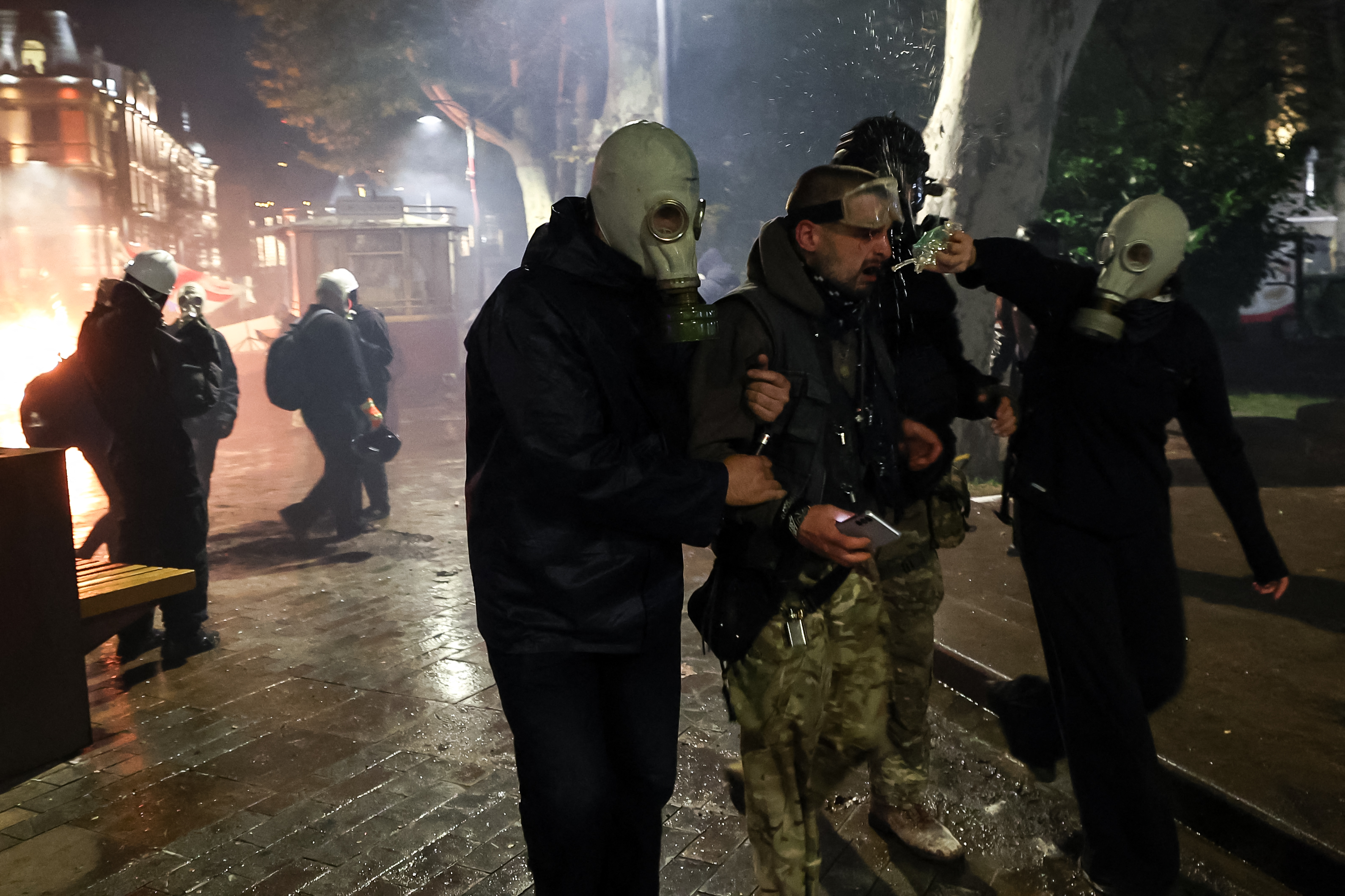 A protester receives help after being hit by tear gas during clashes with riot police during an opposition rally on the day of local elections in central Tbilisi on October 4, 2025. (Photo by Giorgi ARJEVANIDZE / AFP)