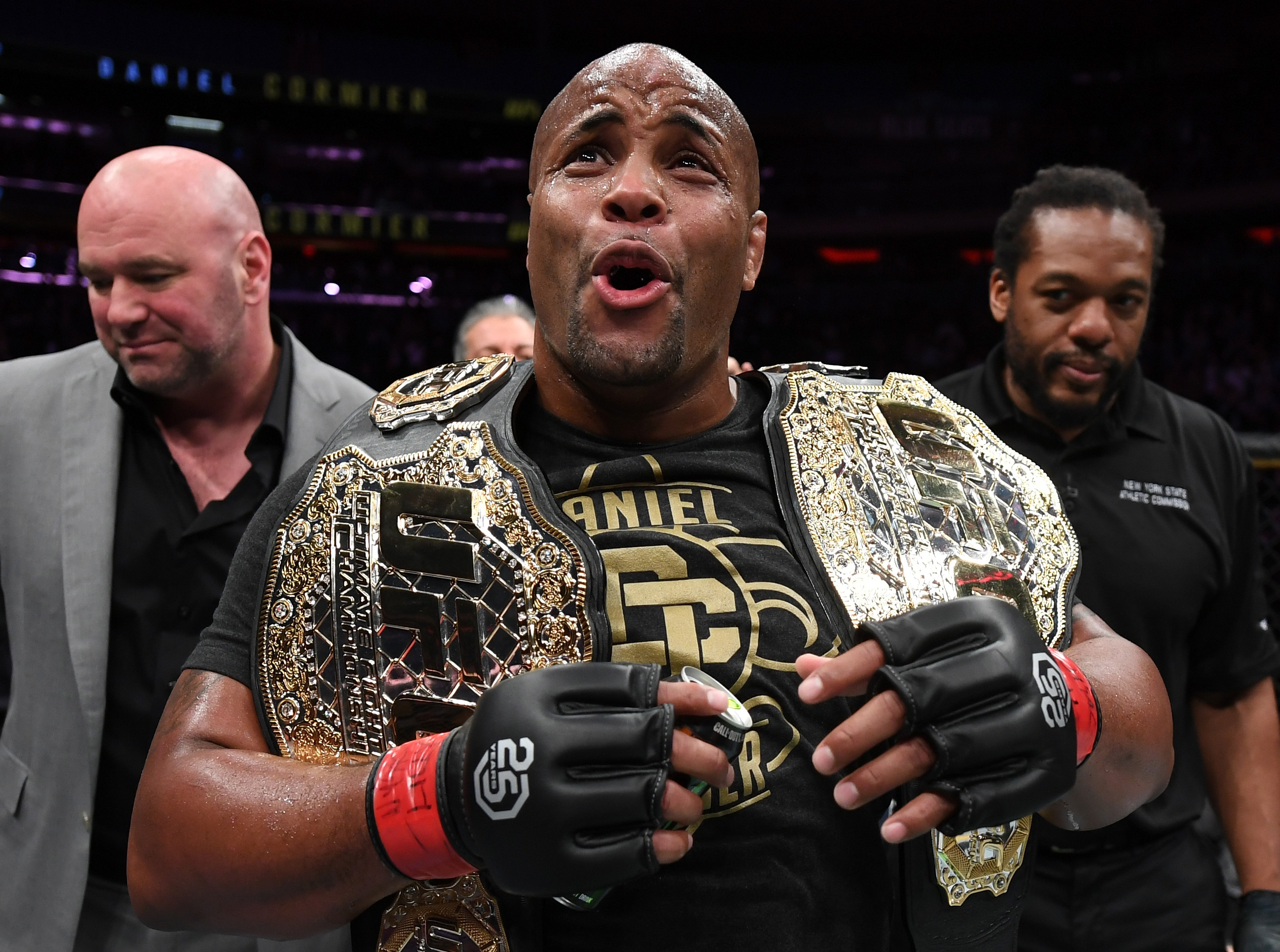 UFC fighter Daniel Cormier holding two championship belts.