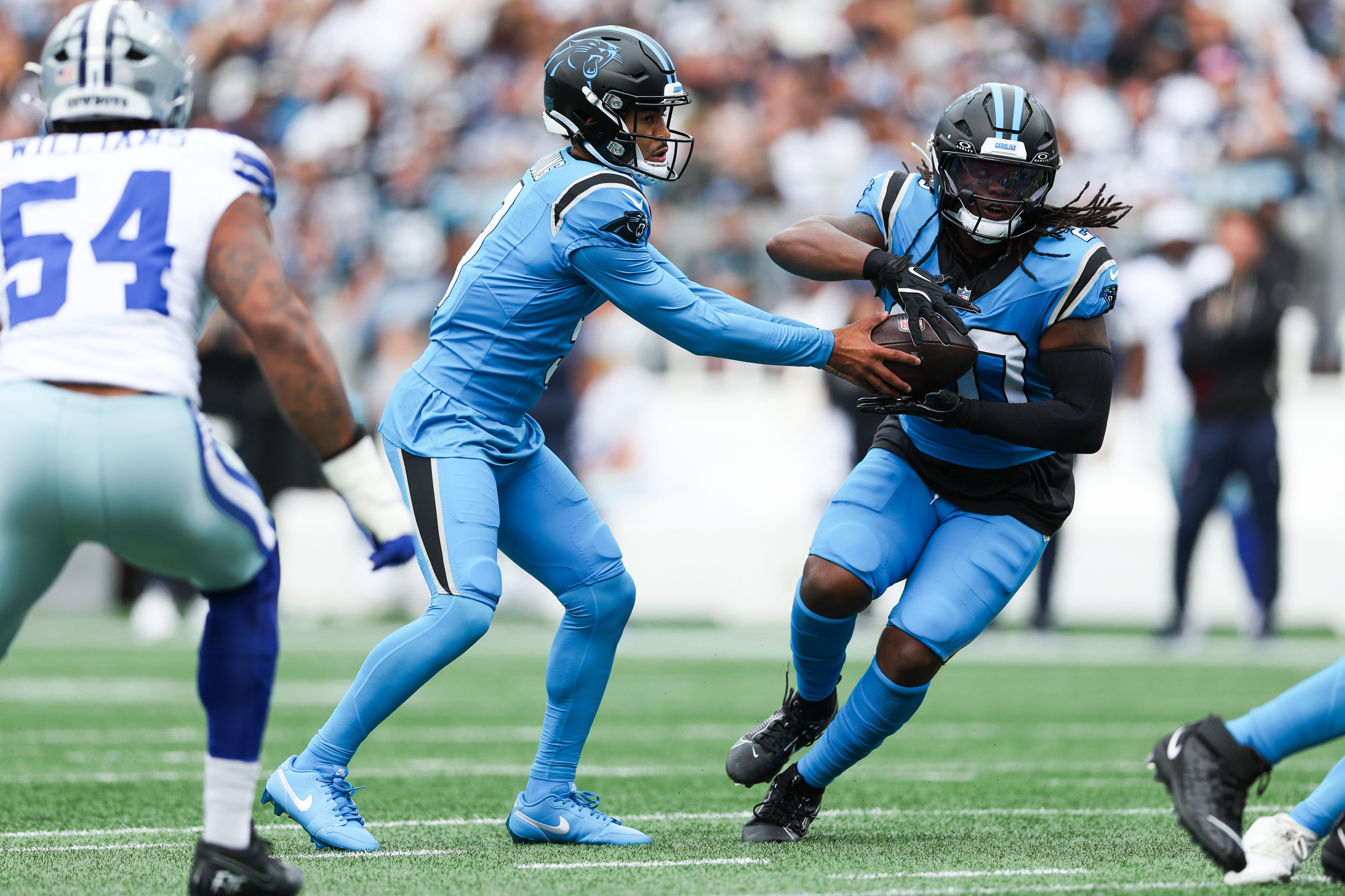 Oct 12, 2025; Charlotte, North Carolina, USA; Carolina Panthers quarterback Bryce Young (9) hands the ball to running back DeeJay Dallas (20) during the first quarter against the Dallas Cowboys at Bank of America Stadium. Mandatory Credit: Cory Knowlton-Imagn Images