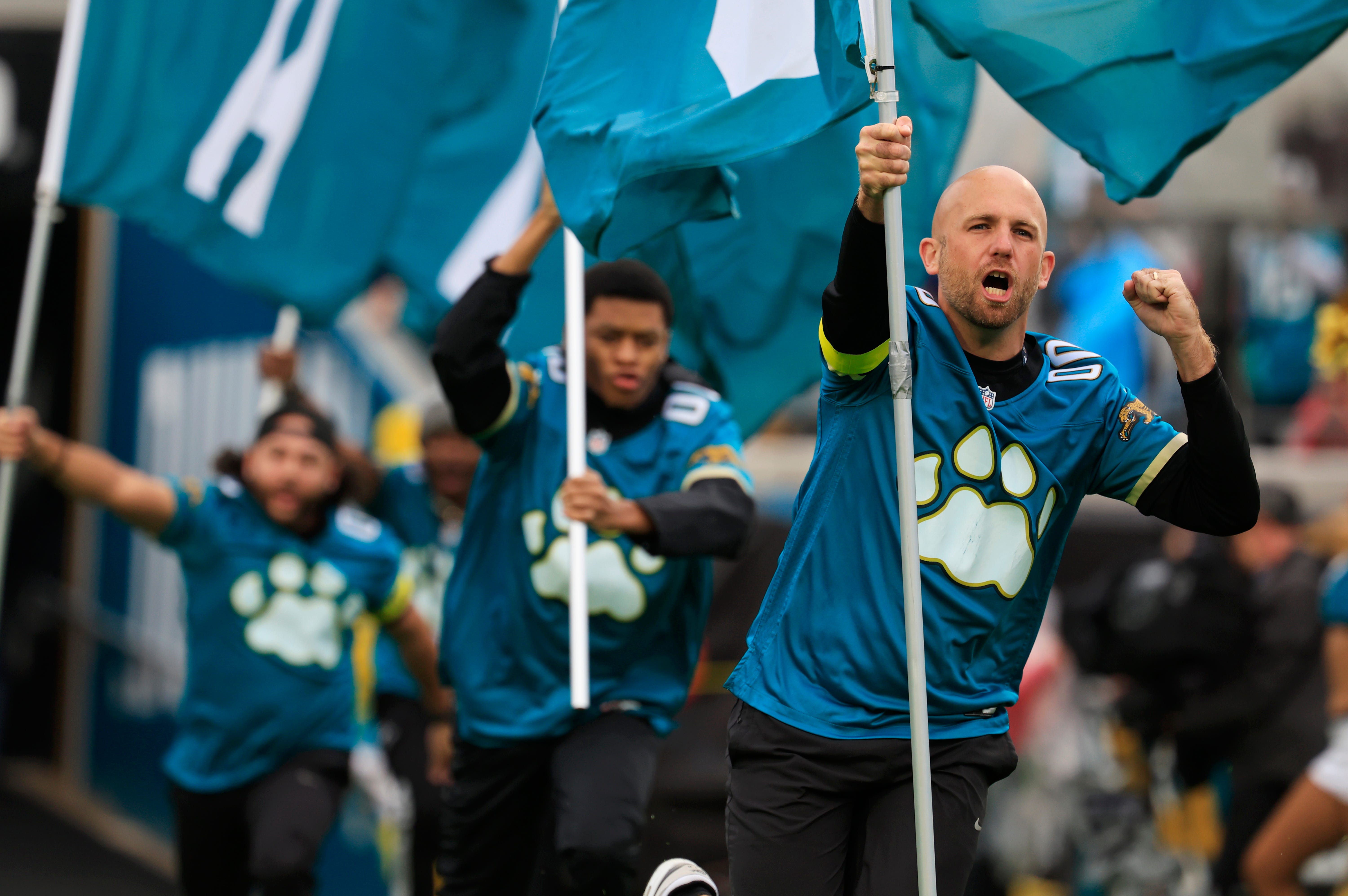 Jacksonville Jaguars Jax Pack flag bearers run on the field before an NFL football game at EverBank Stadium, Sunday, Dec. 7, 2025, in Jacksonville, Fla. The Jaguars defeated the Colts 36-19.