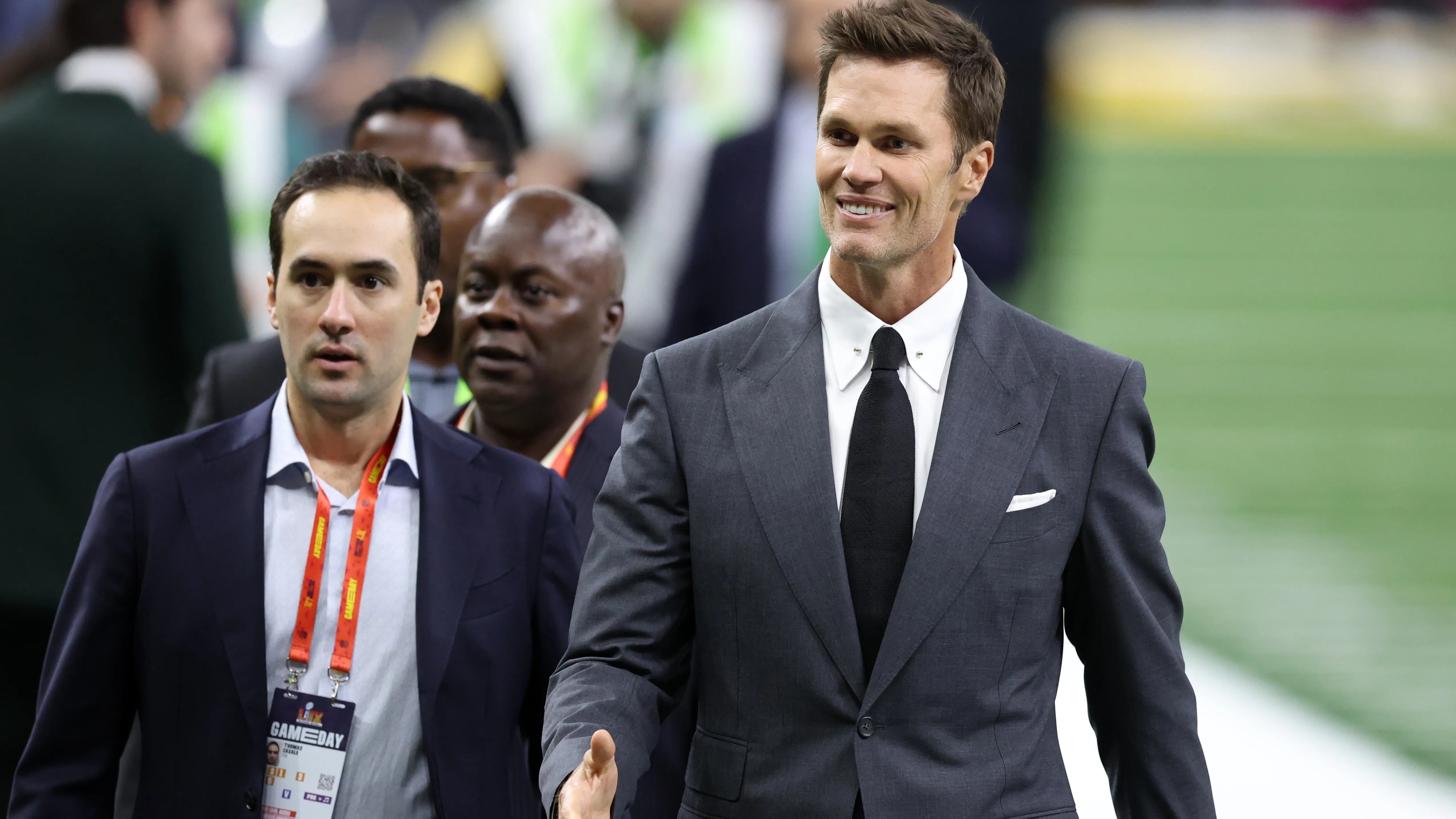 Tom Brady walking across a football field before a game.
