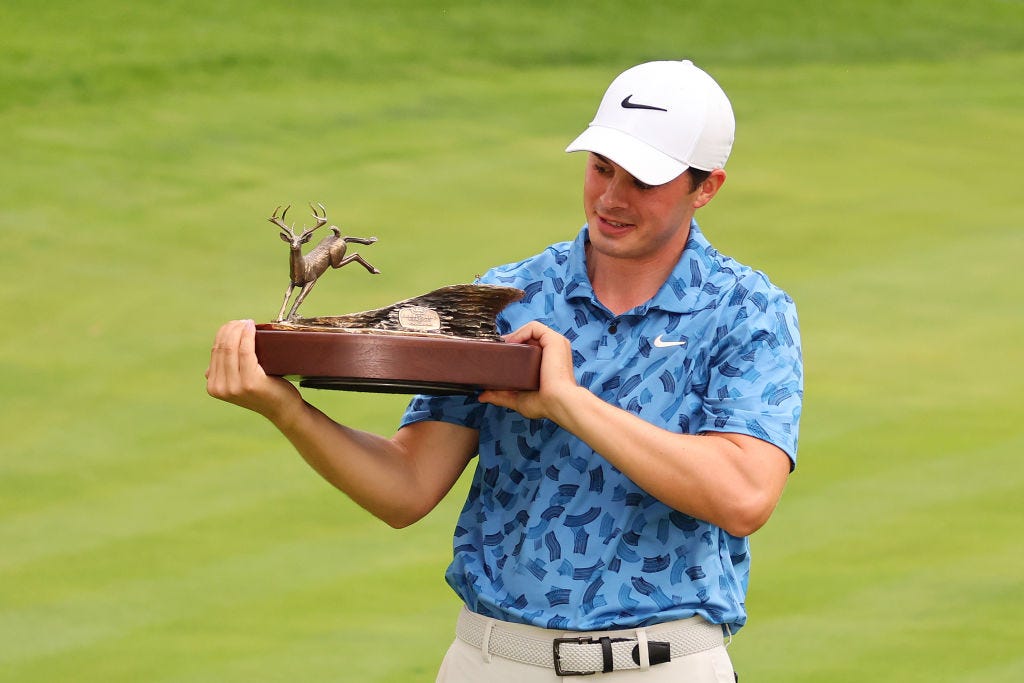 Davis Thompson of St. Simons Island, Ga., admires the trophy he won for the 2024 John Deere Classic.