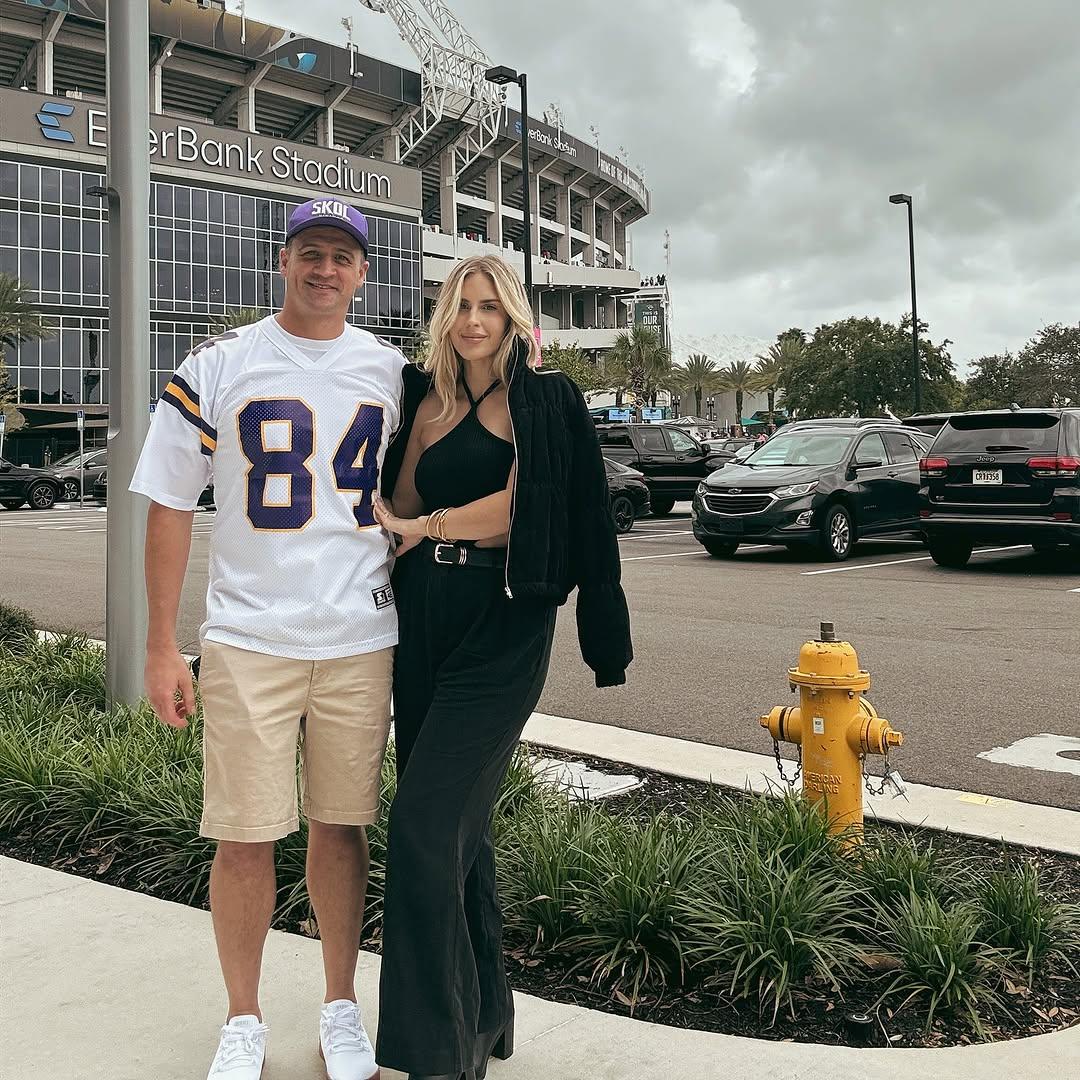 Kayla Reid and Ryan Lochte posing in front of a football stadium.