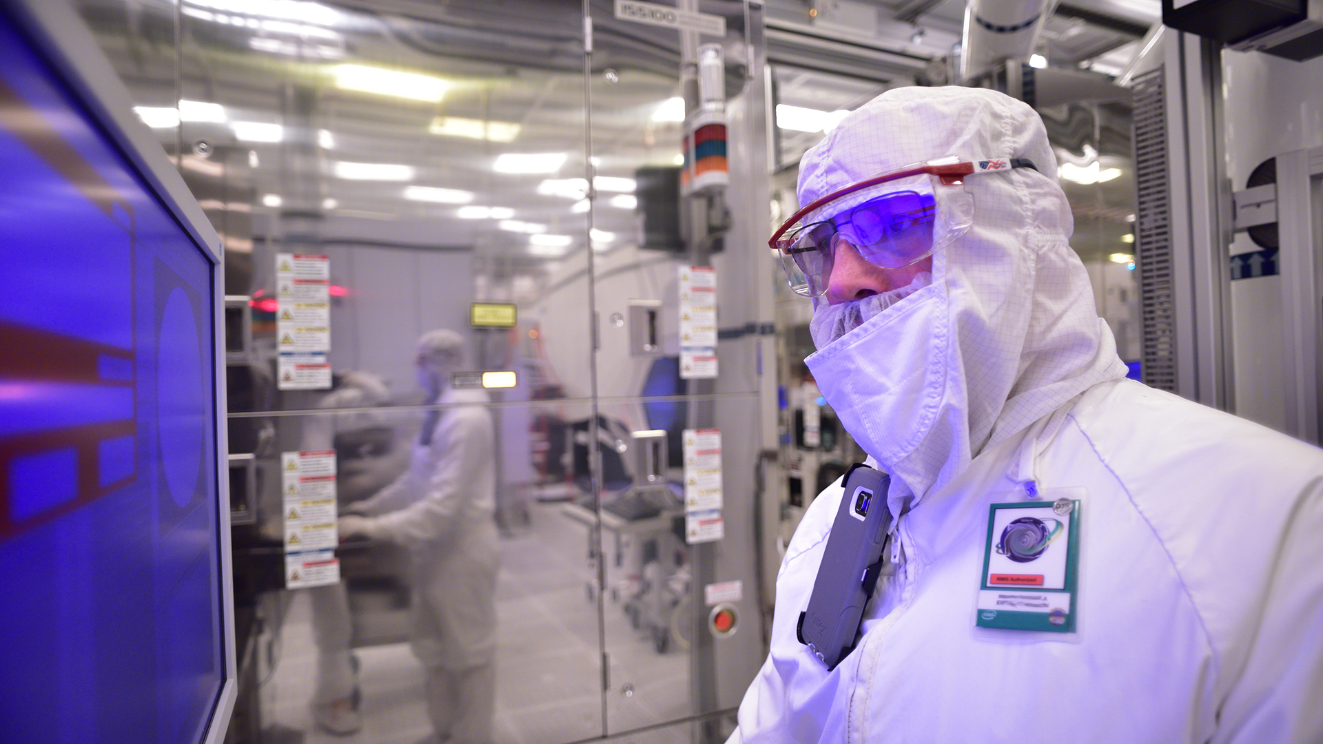 Intel manufacturing shot of employee in bunny suit (protective gear) in front of screen