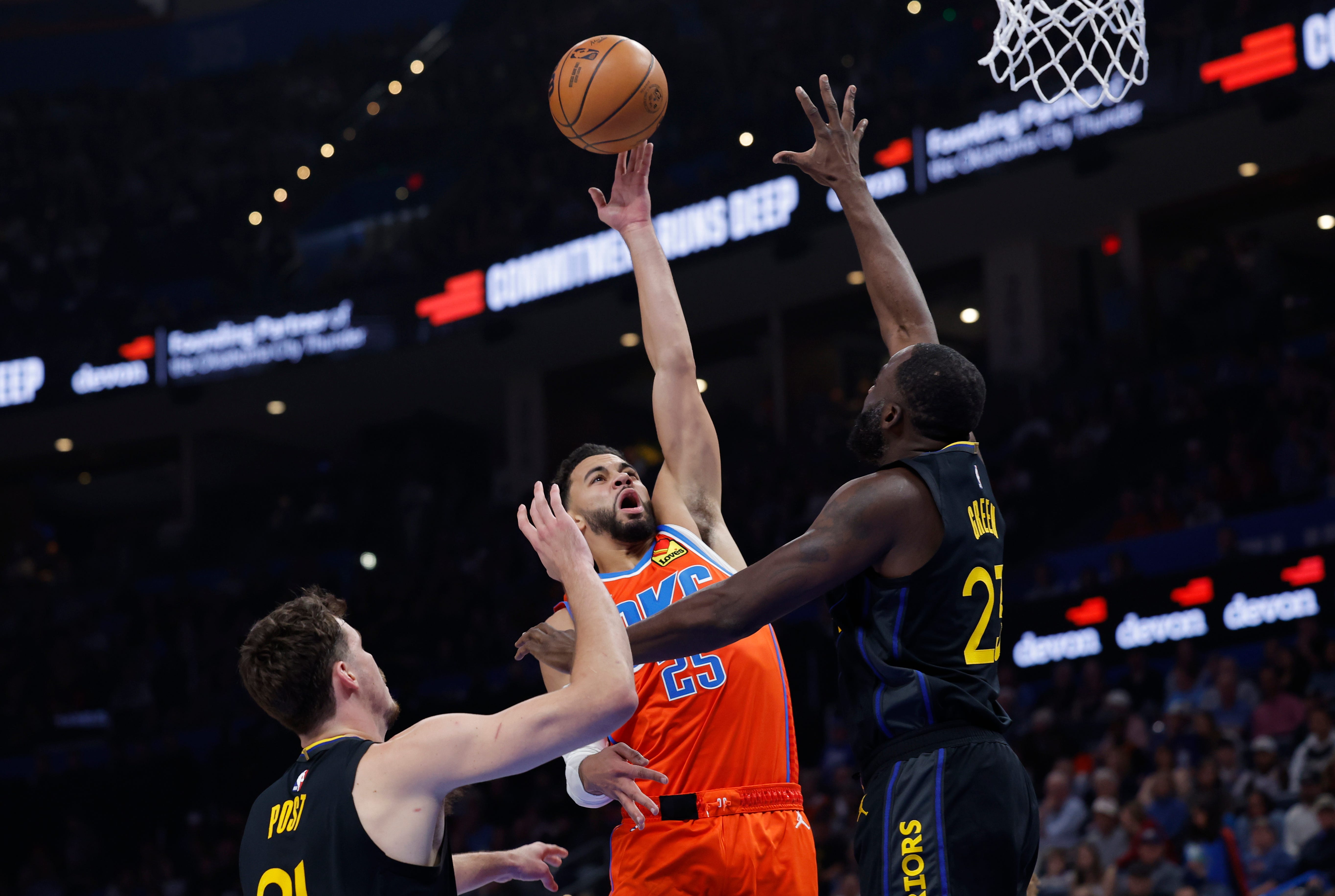 Nov 11, 2025; Oklahoma City, Oklahoma, USA; Oklahoma City Thunder guard Ajay Mitchell (25) goes to the basket between Golden State Warriors center Quinten Post (21) and forward Draymond Green (23) during the second quarter at Paycom Center. Mandatory Credit: Alonzo Adams-Imagn Images
