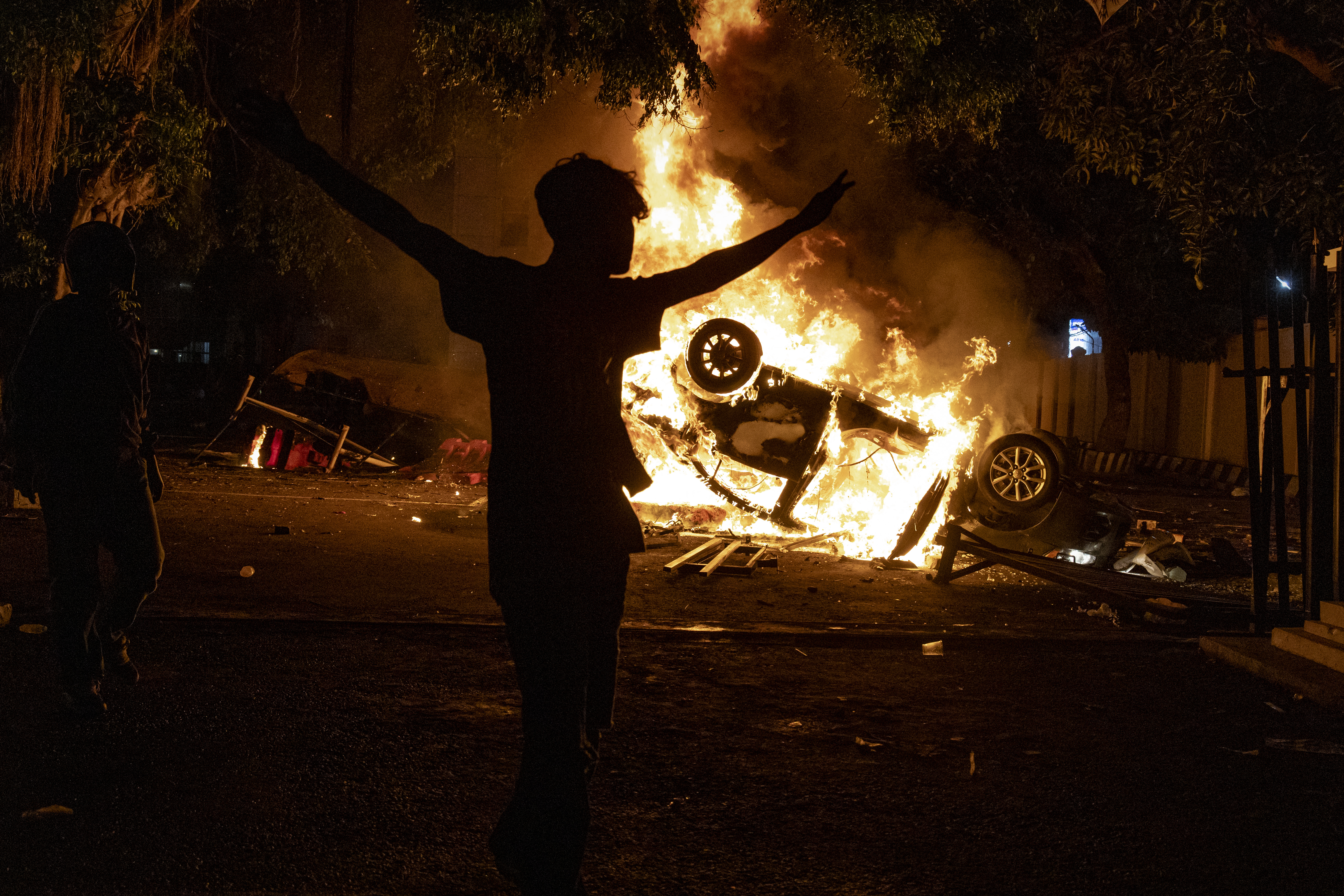 YOGYAKARTA, INDONESIA - AUGUST 29: A man walk pass a burning car after being set ablaze during a protest at Yogyakarta Police headquarterson August 29, 2025 in Yogyakarta, Indonesia. Protesters demand economic justice and government accountability as tensions rose in Jakarta and elsewhere following the death of a ride-share driver, who was killed after a police vehicle struck him during demonstrations over living costs and wage reforms. (Photo by Ulet Ifansasti/Getty Images)