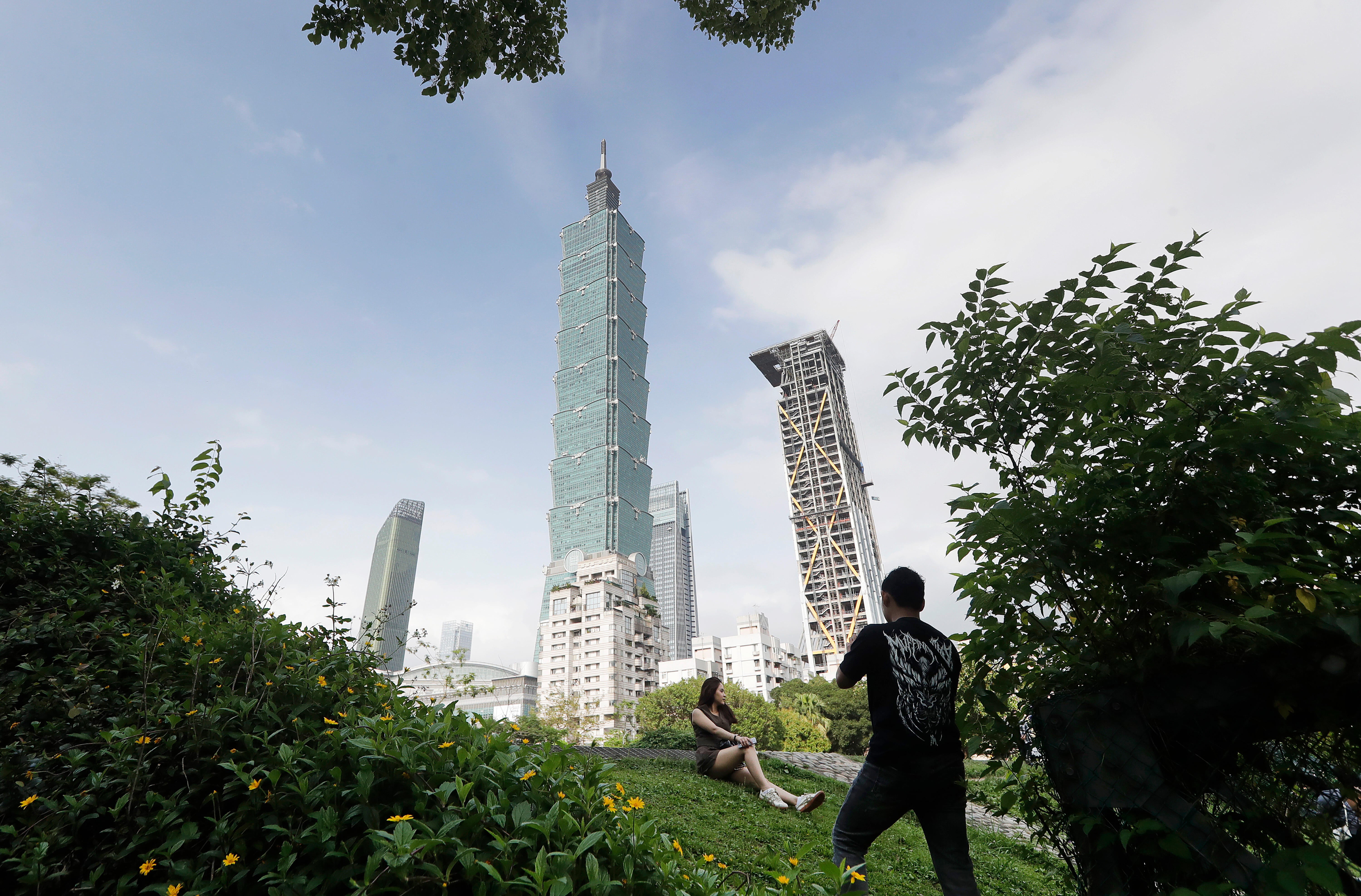People take photos with the iconic Taipei 101 skyscraper in the background in Taipei, Taiwan, on April 27, 2025. / Credit: ChiangYing-ying / AP