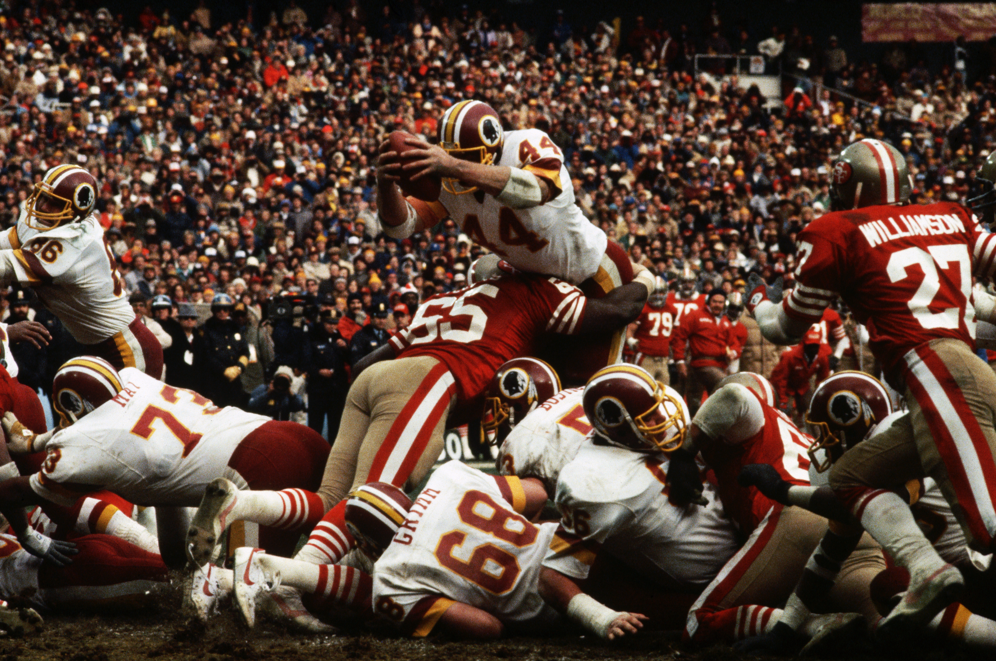 Washington Redskins running back John Riggins leaps over the defense to score a touchdown during the NFC Championship game against the San Francisco 49ers. The linebackers on the ground are May (#73), and Russ Grimm (#68). (Photo by &copy; Wally McNamee/CORBIS/Corbis via Getty Images)