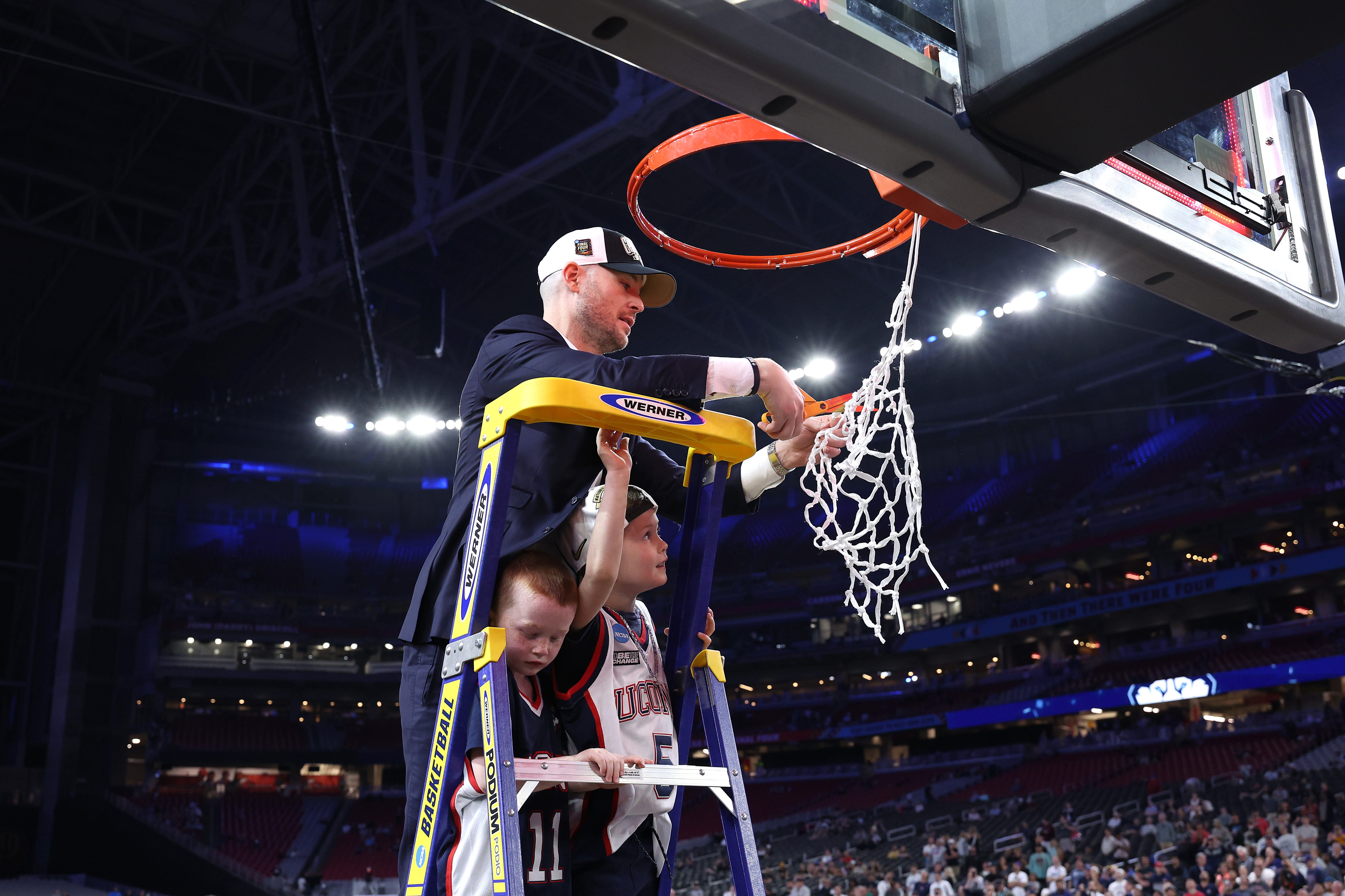 Assistant coach Luke Murray of the Connecticut Huskies cuts down the net after beating the Purdue Boilermakers, 75-60, to win the NCAA Men's Basketball Tournament National Championship game at State Farm Stadium on April 8, 2024 in Glendale, Arizona.