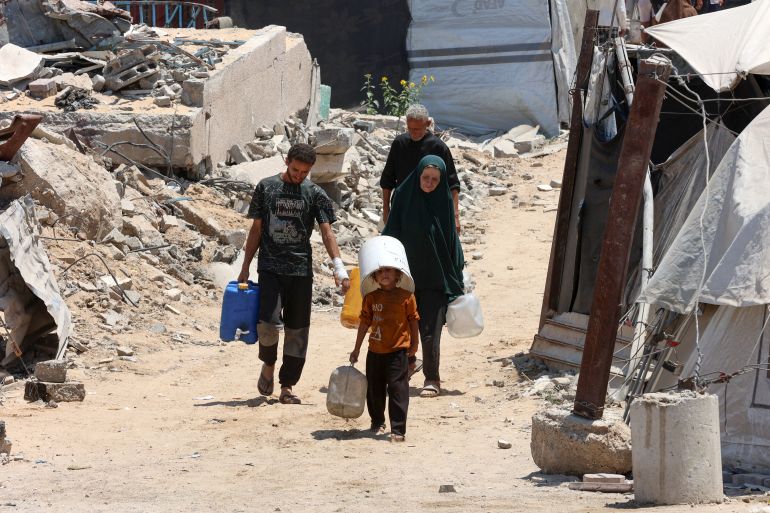 A Palestinian child covers his head with a bucket as he and others carry gallons of clear water from a distribution point in Gaza City on August 1, 2025. (Photo by Omar AL-QATTAA / AFP)