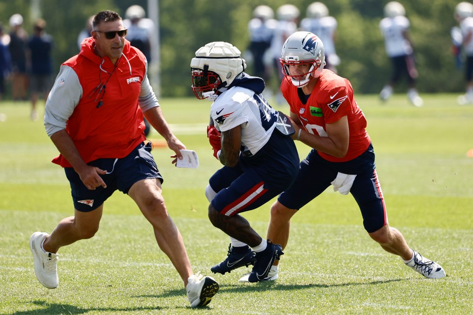 FOXBOROUGH, MA - JULY 29: Head coach Mike Vrabel of the New England Patriots gets involved in practice as quarterback Drake Maye #10 fakes a handoff to Trayveon Williams #49 during training camp at Gillette Stadium on July 29, 2025 in Foxborough, Massachusetts.(Photo By Winslow Townson/Getty Images)